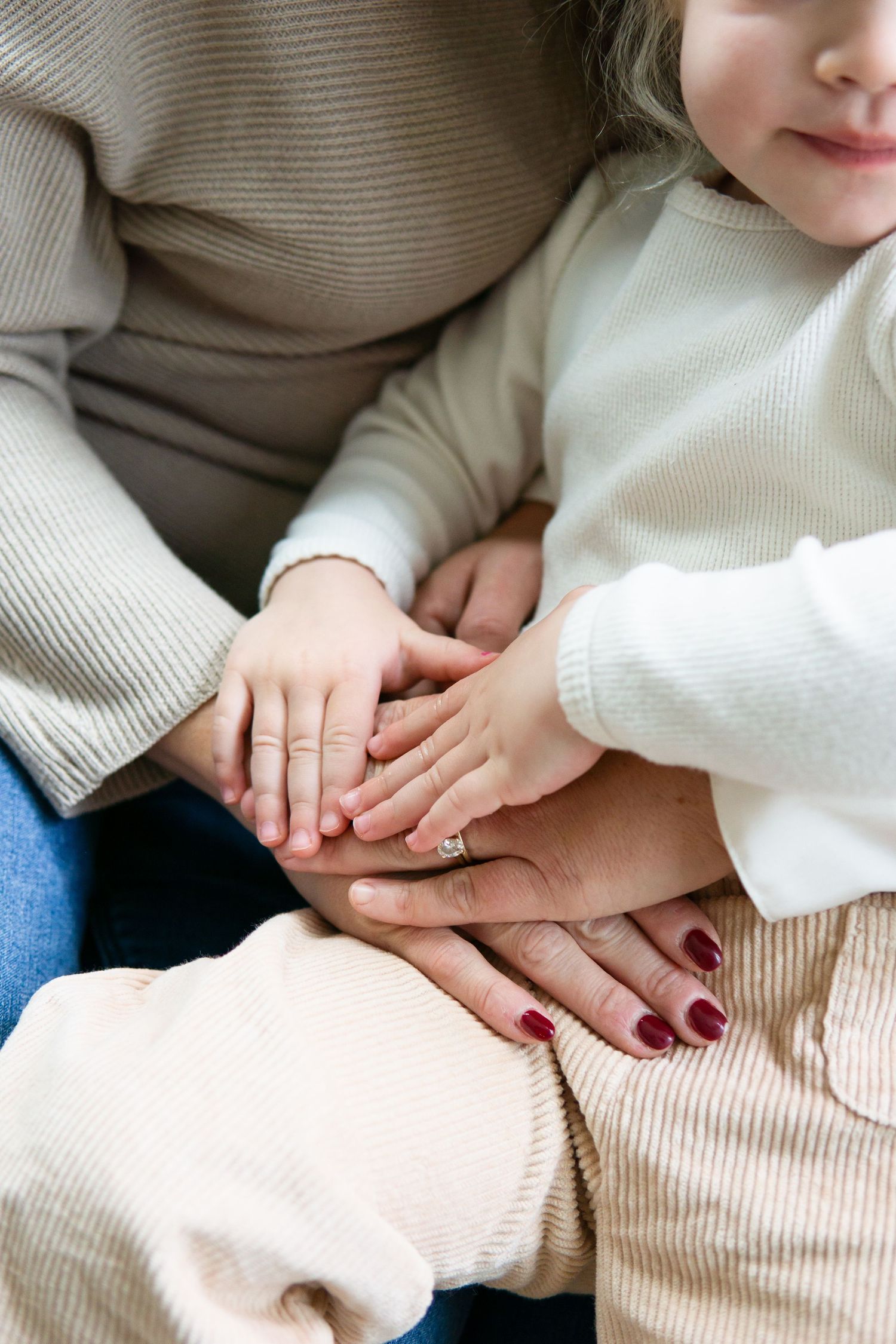 Hands with an engagement ring stacked together in a tender moment.