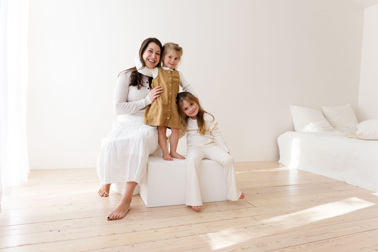 Family enjoying tender moments together in a bright white minimalist space.