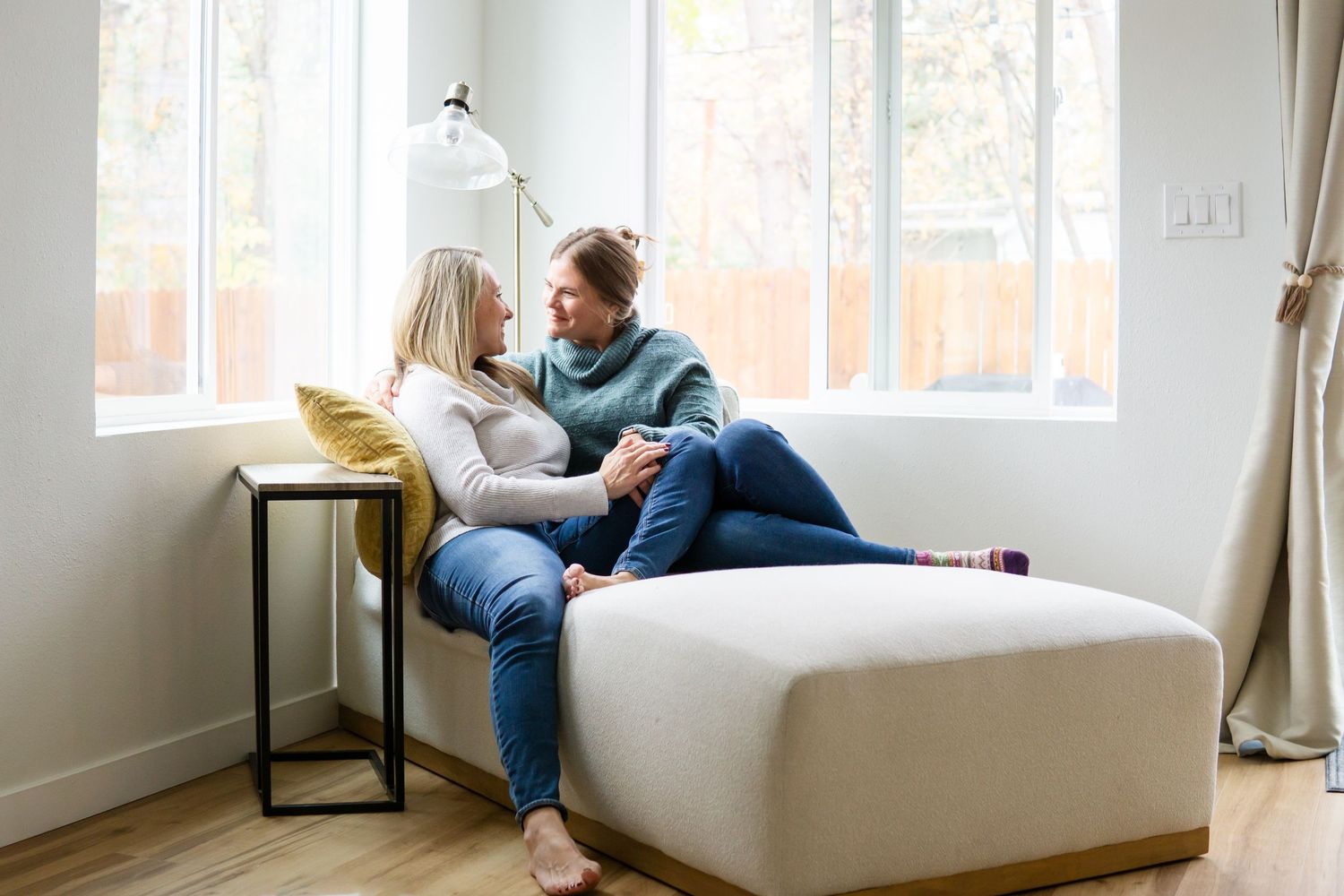 A cozy scene on a white ottoman by a window with natural light streaming in.