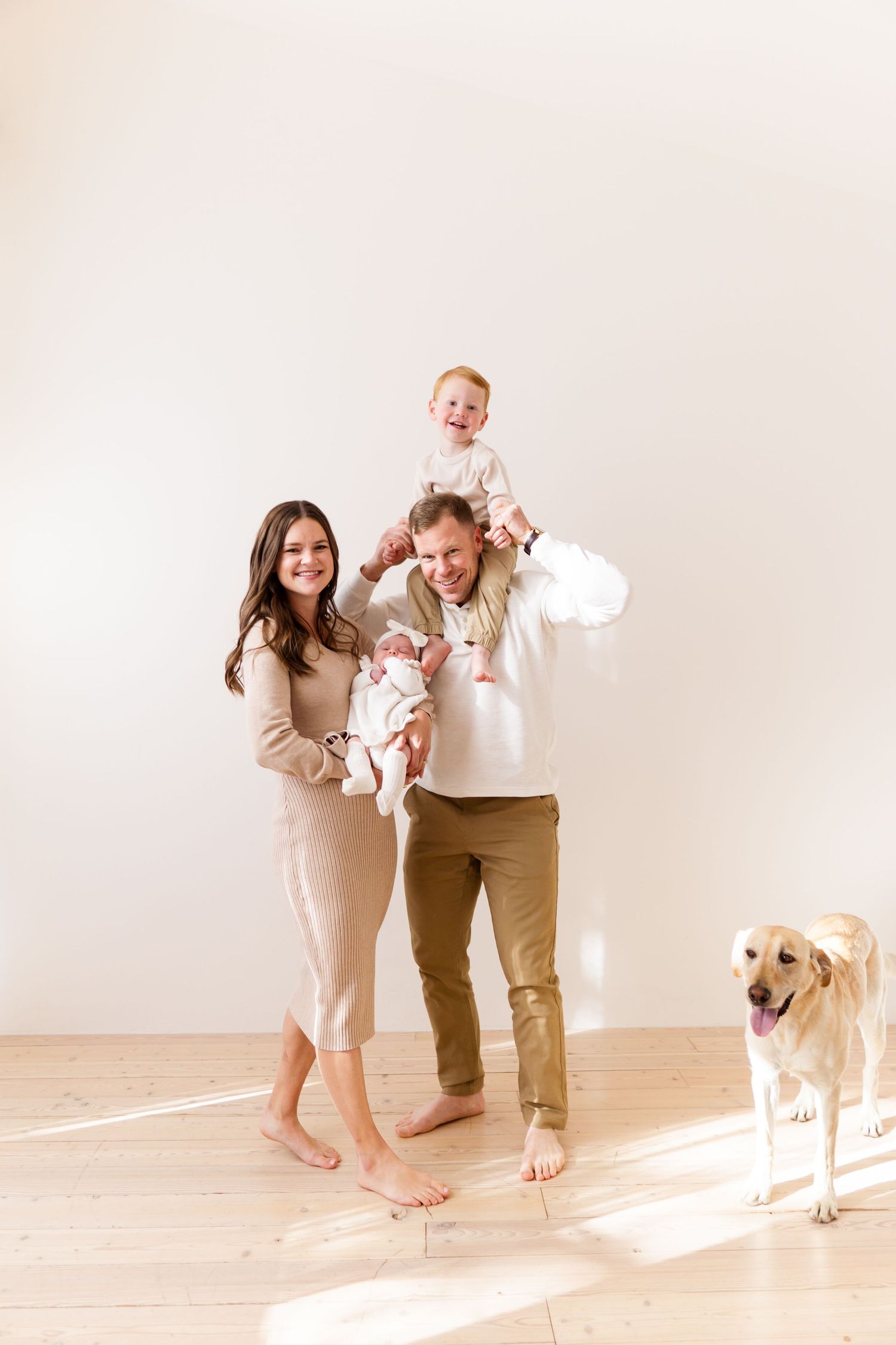 Family and dog playing together in a bright minimalist room with natural light.