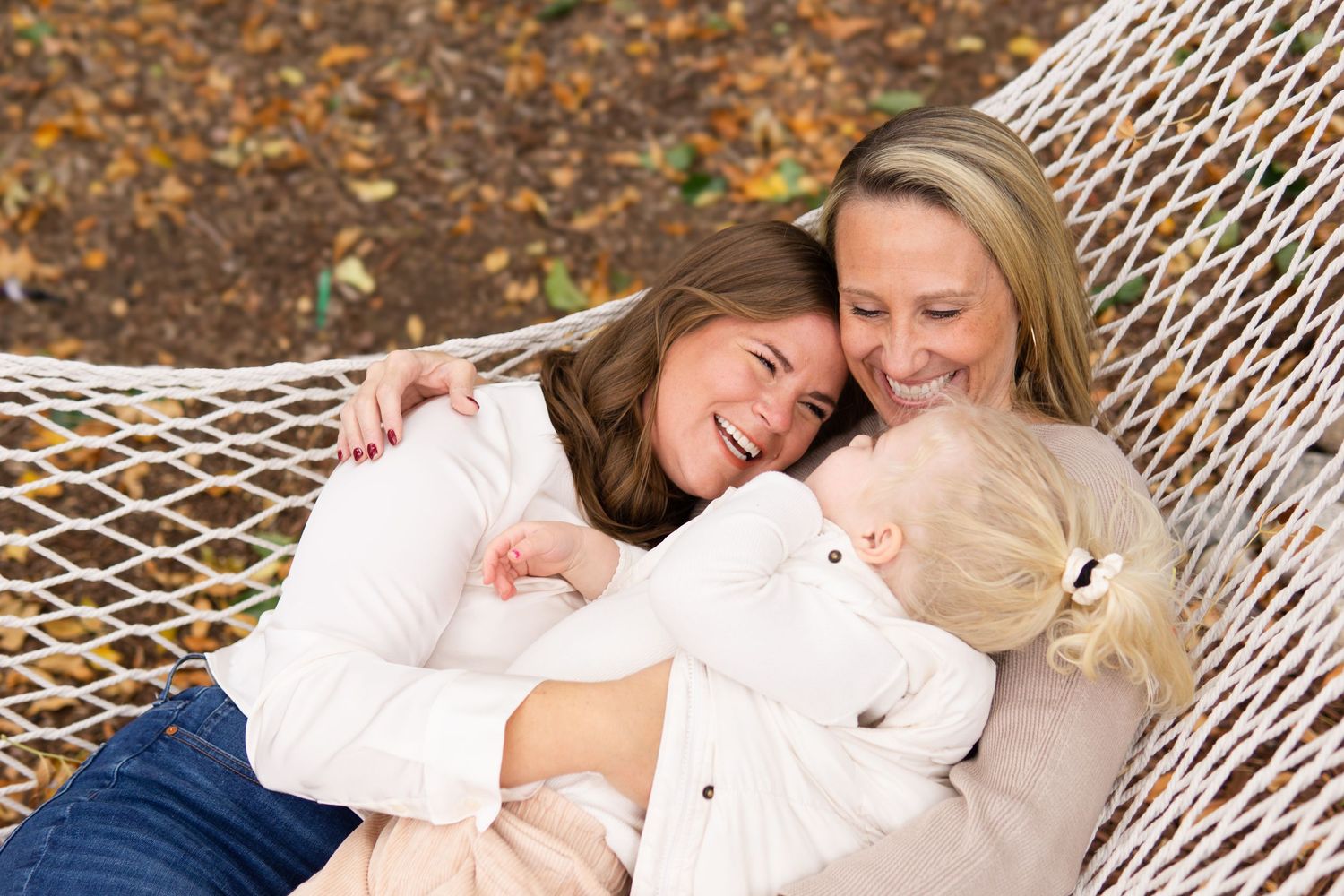 A relaxing moment in a white hammock during autumn surrounded by fallen leaves.