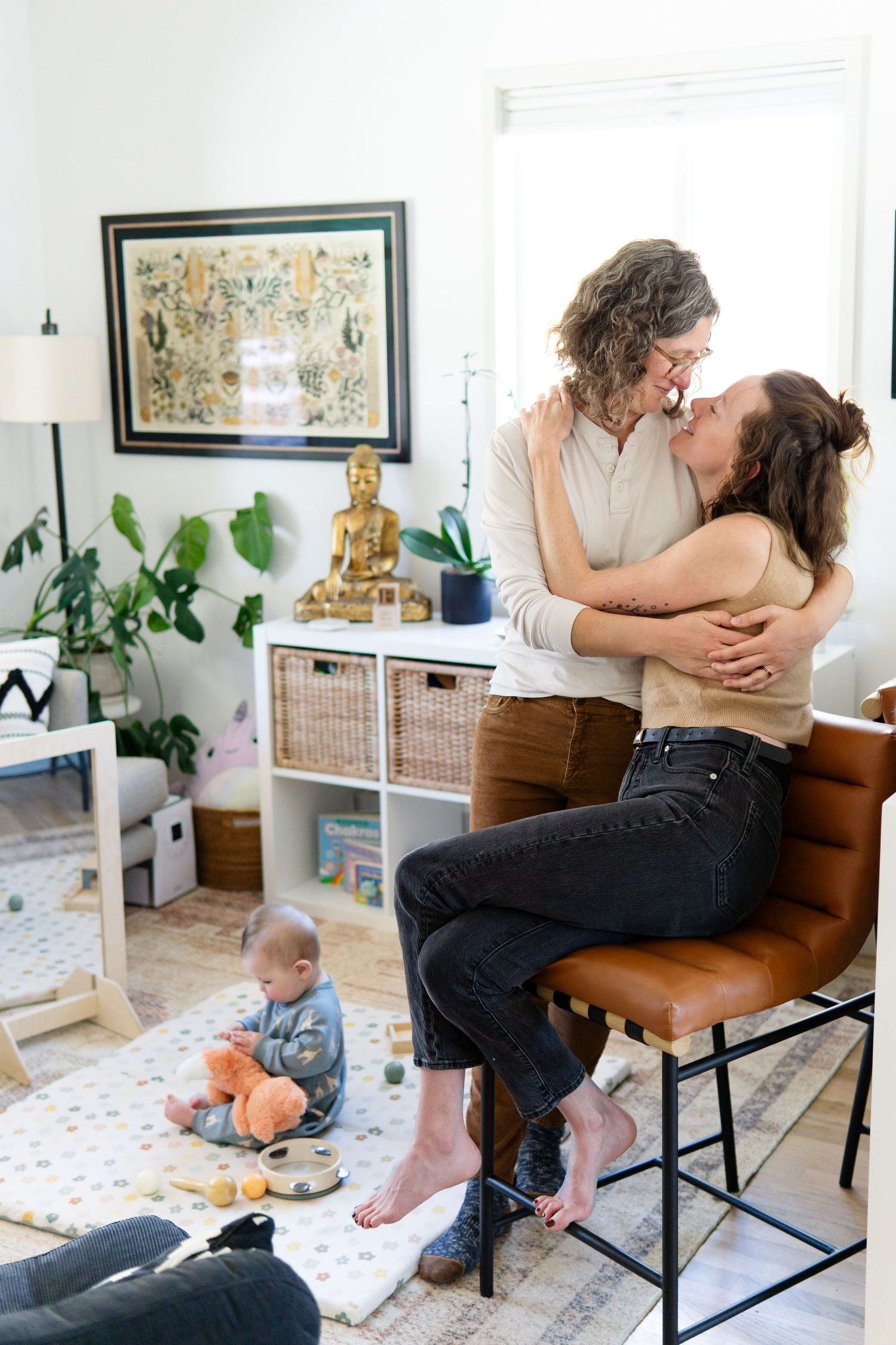 A bright modern living room with indoor plants, a Buddha statue, and woven storage baskets.