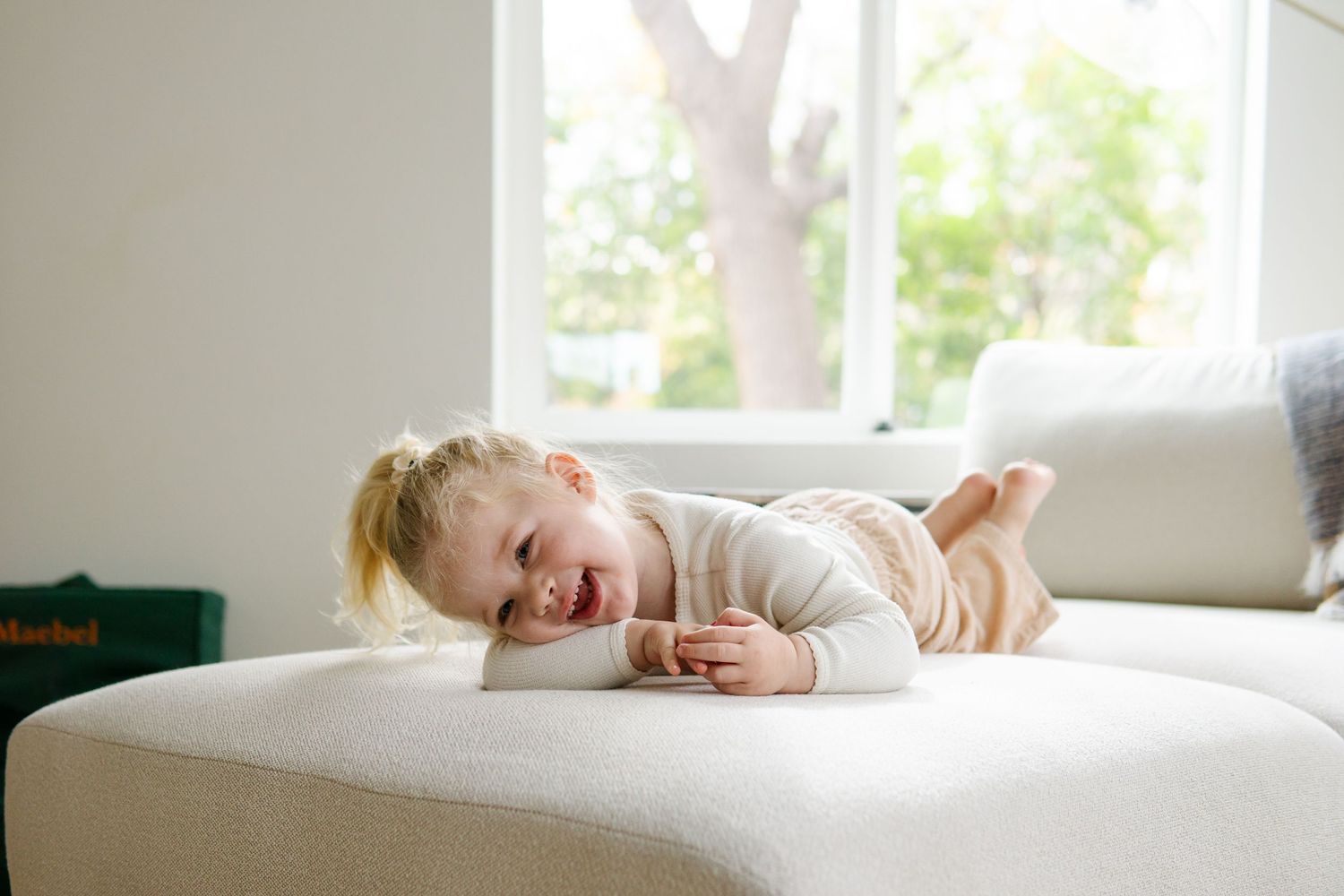 A joyful moment on a white couch with natural light from large windows.