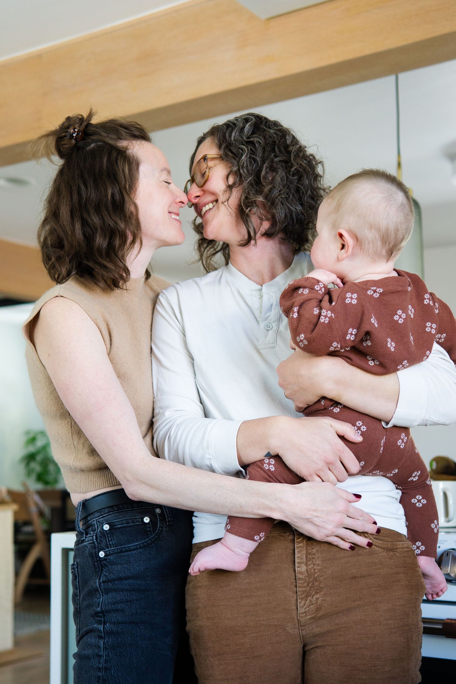 Tender family embrace captured in casual home setting with natural lighting.