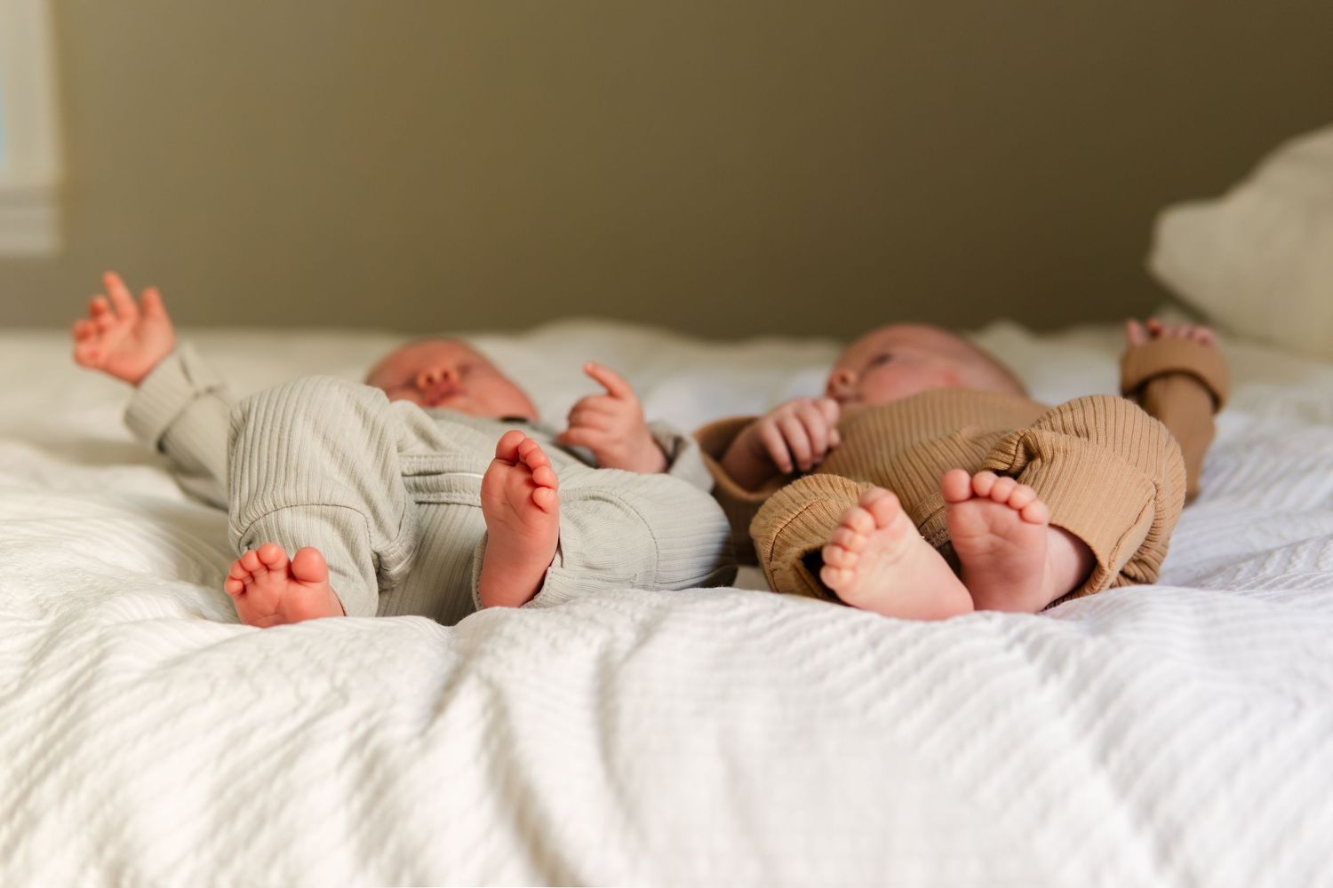 Baby feet lined up on white bedding in sequence.
