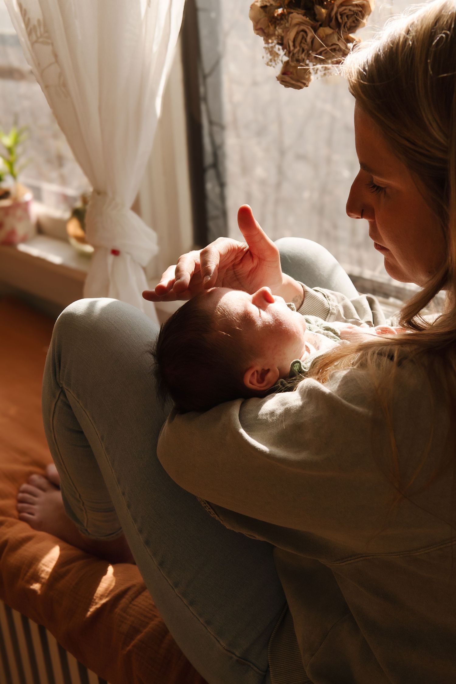 A tender moment captured in warm sunlight through sheer curtains.