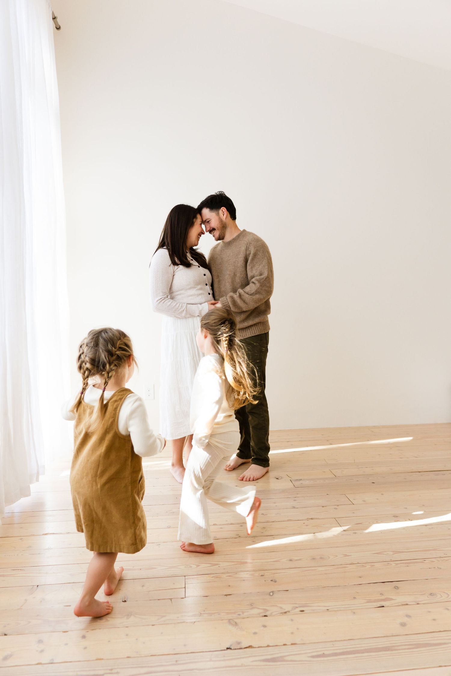 People playing and dancing in a minimalist white room with natural light streaming in.
