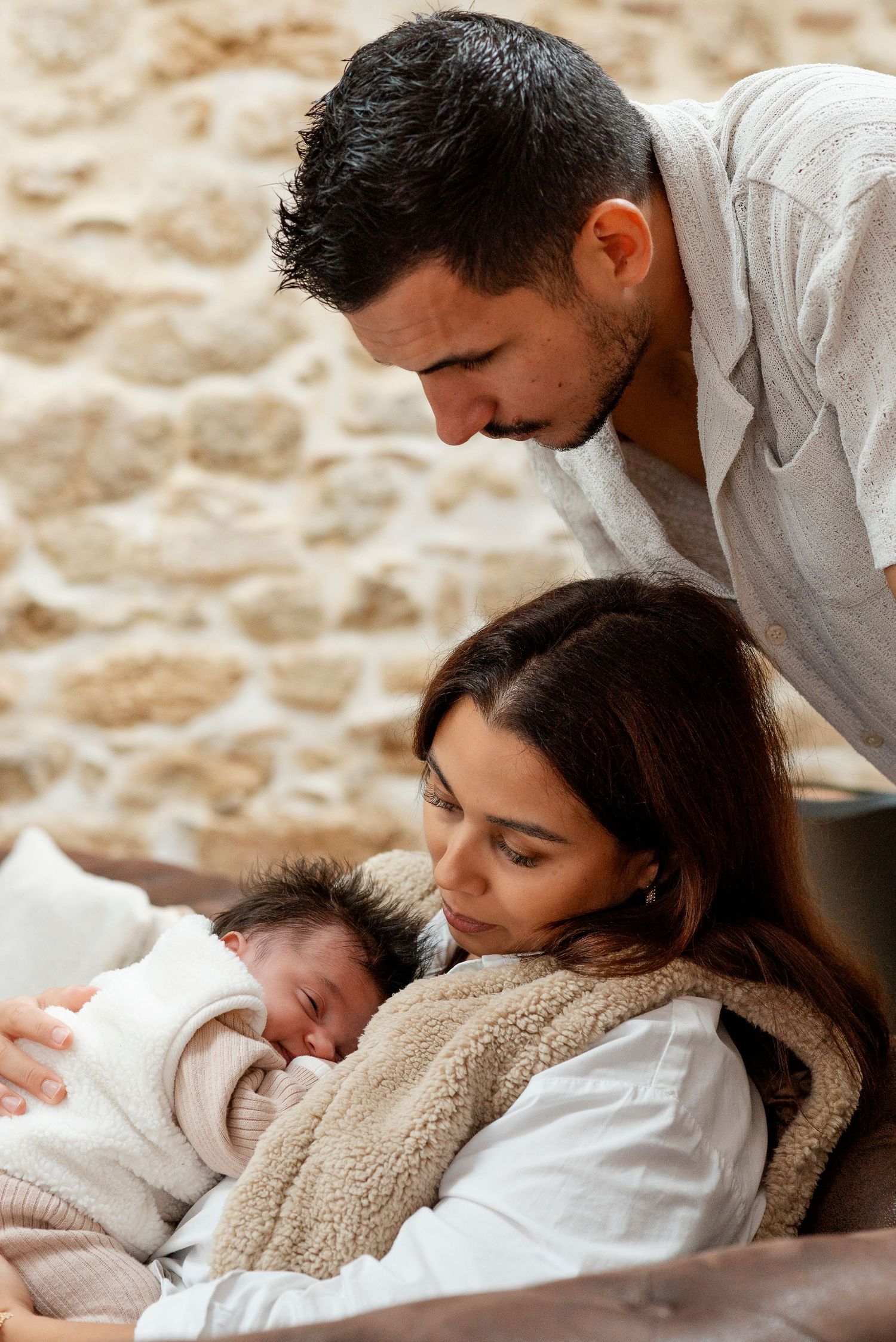 A family shares an intimate moment together while resting on a cozy bed.
