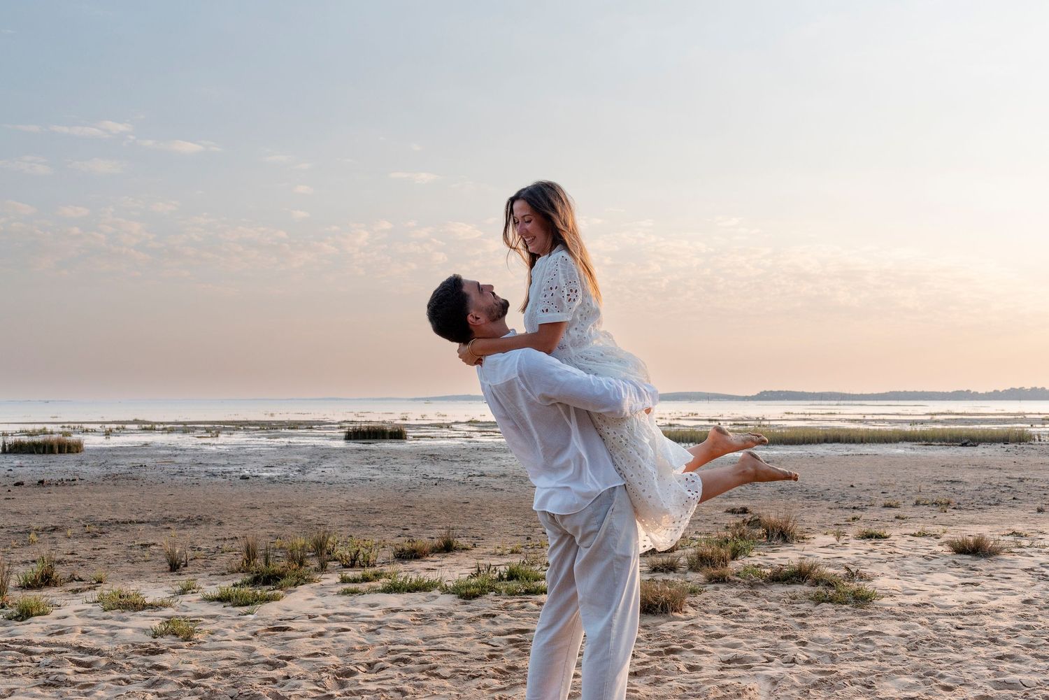Couple embracing on a scenic beach during golden hour sunset.