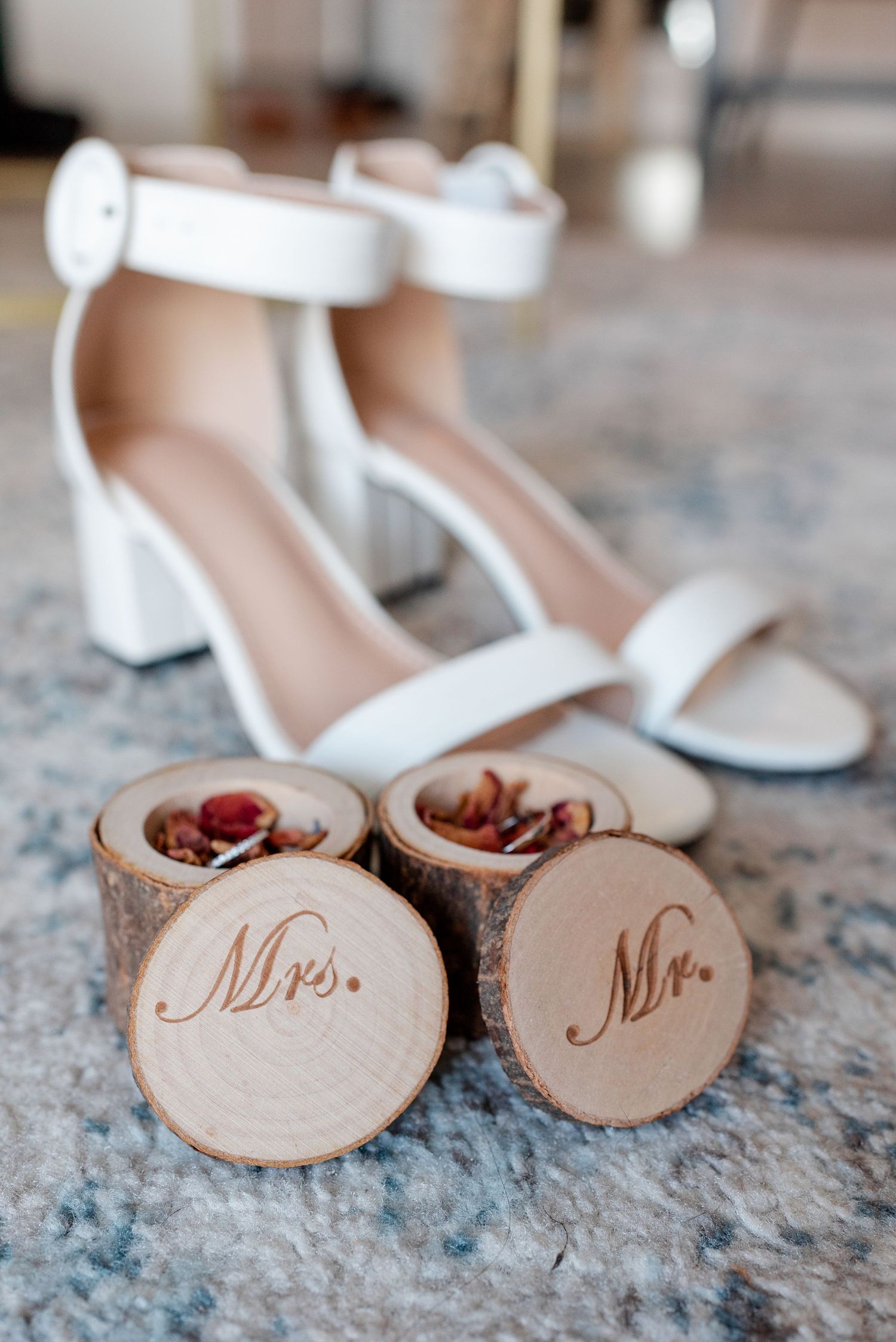 Small wooden wedding ring holder discs with Mr and Mrs text burned into them on a granite countertop surface.
