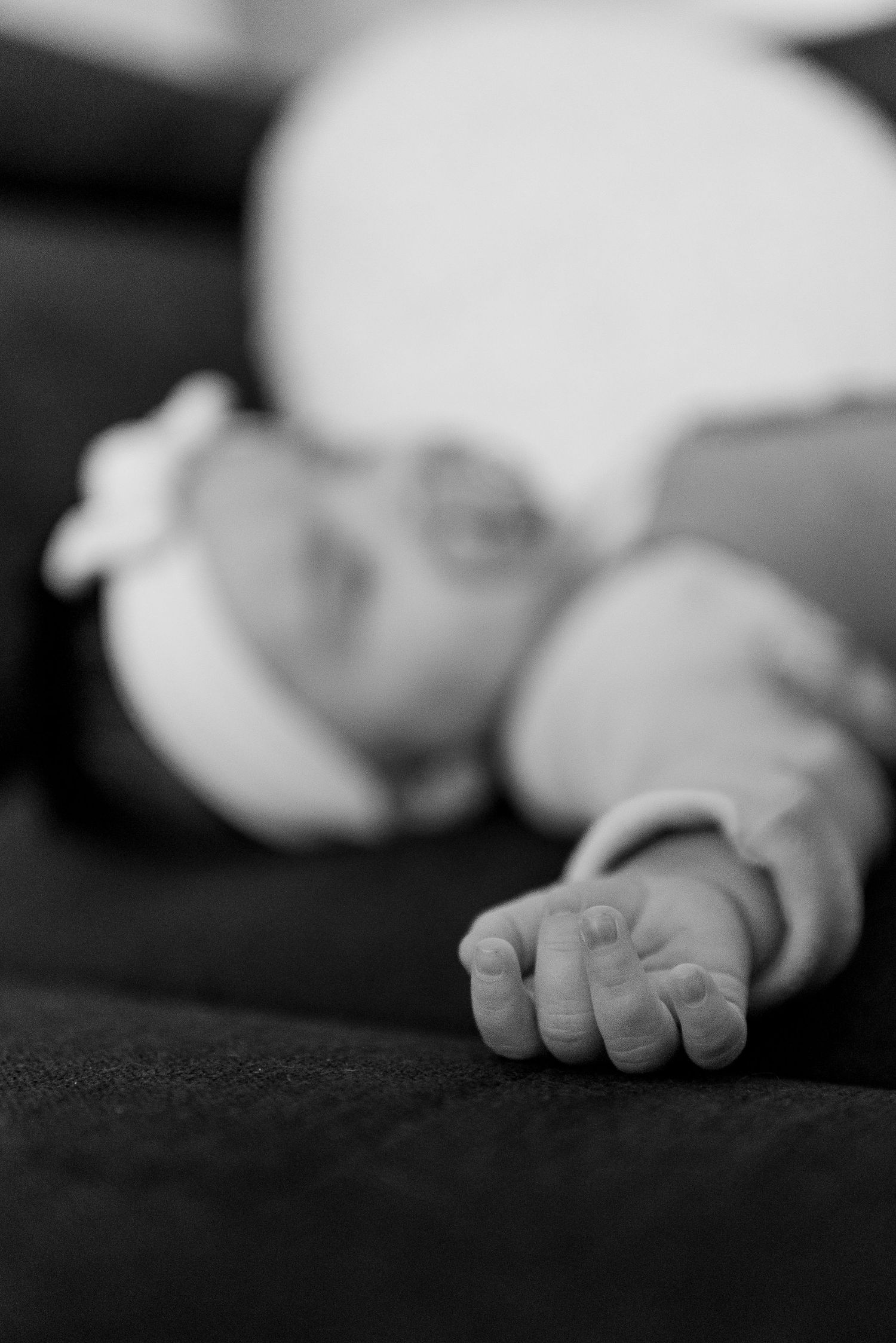 Close-up black and white photograph of tiny baby feet against a dark background.