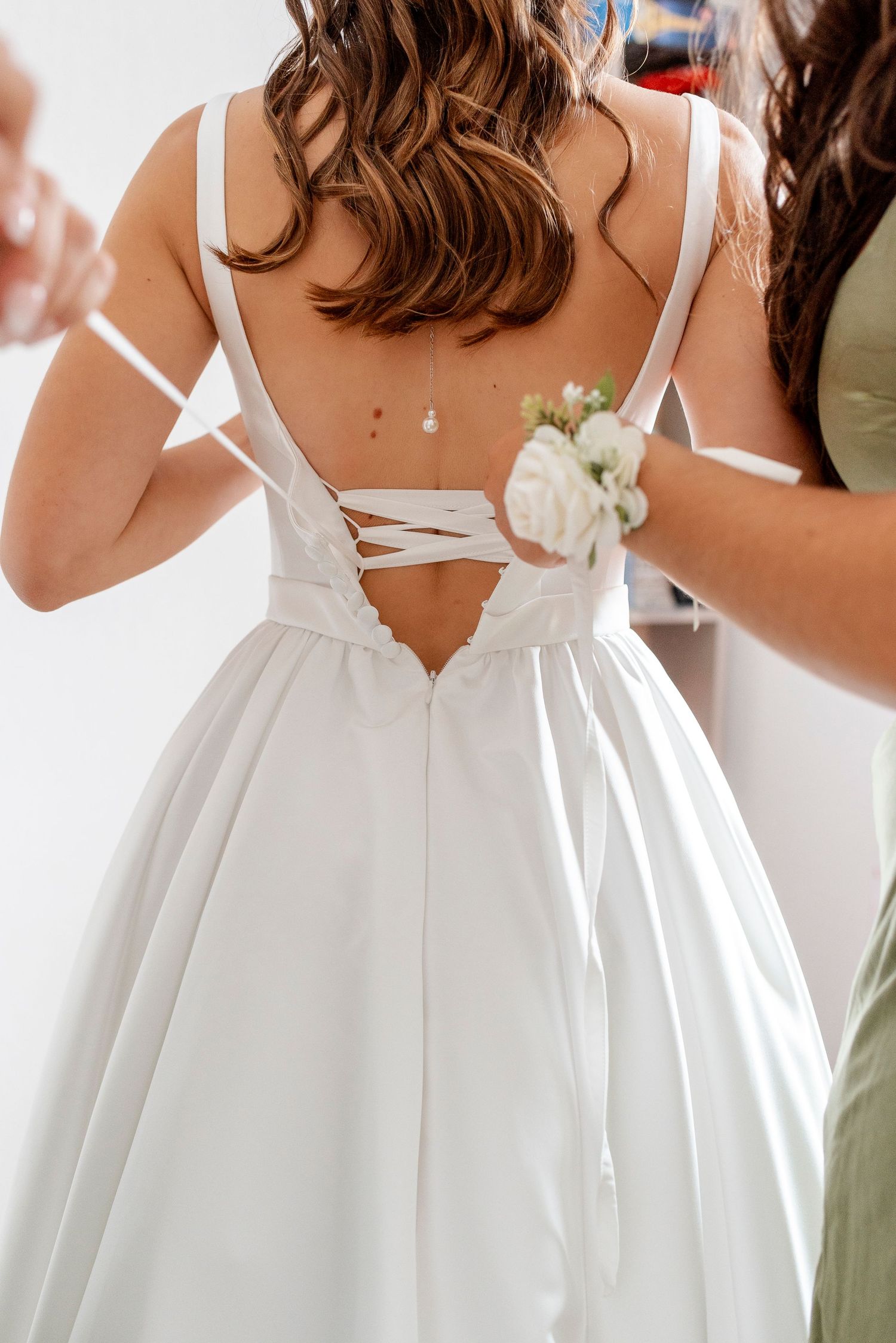 Back details of white wedding dresses with straps and flowing skirts.