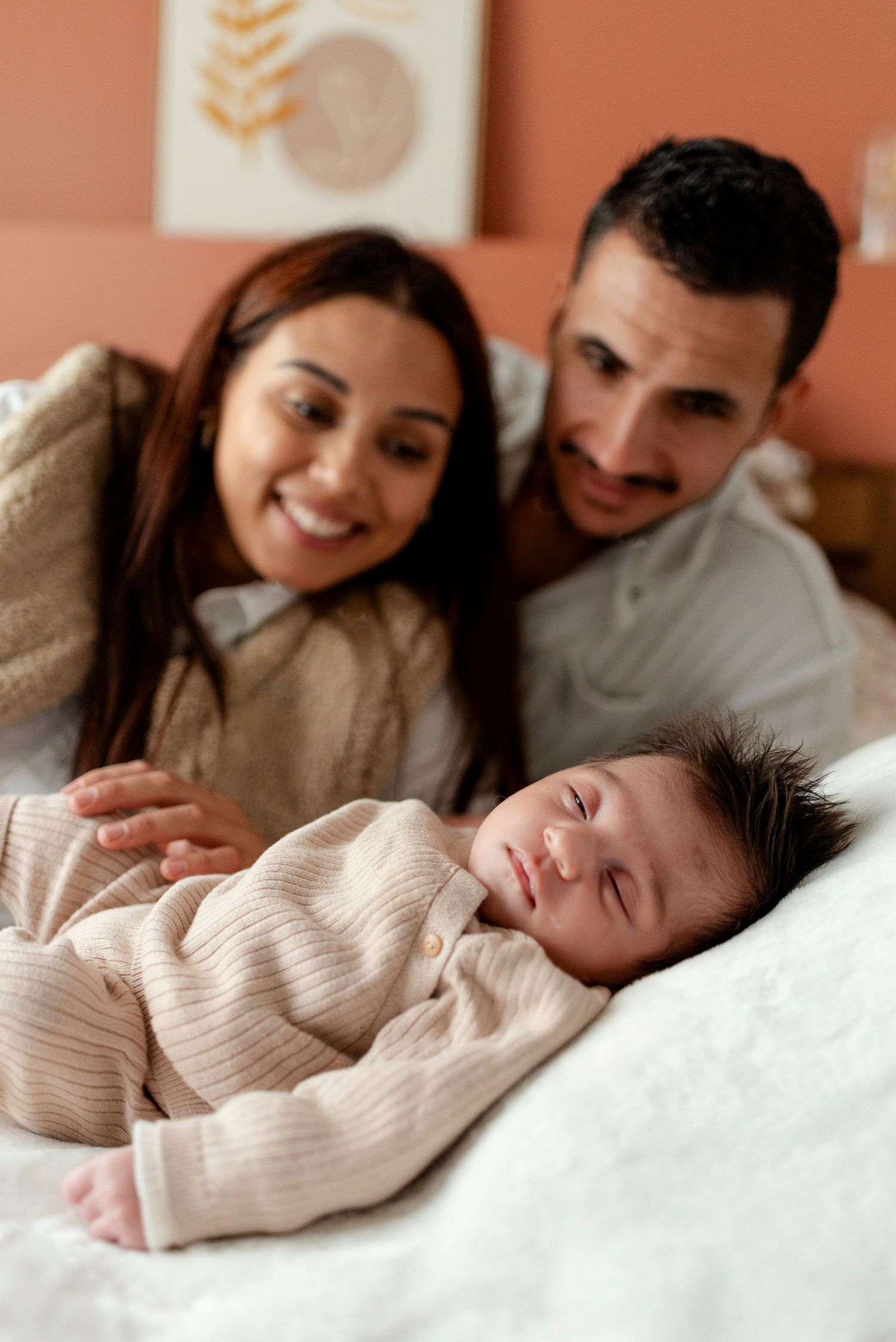 A sleeping baby in a beige sweater rests peacefully while being watched.