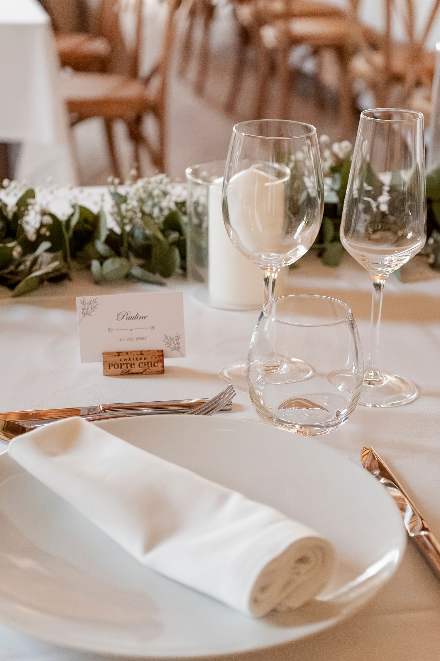 Elegant table setting with wine glasses, white plates and folded napkins.