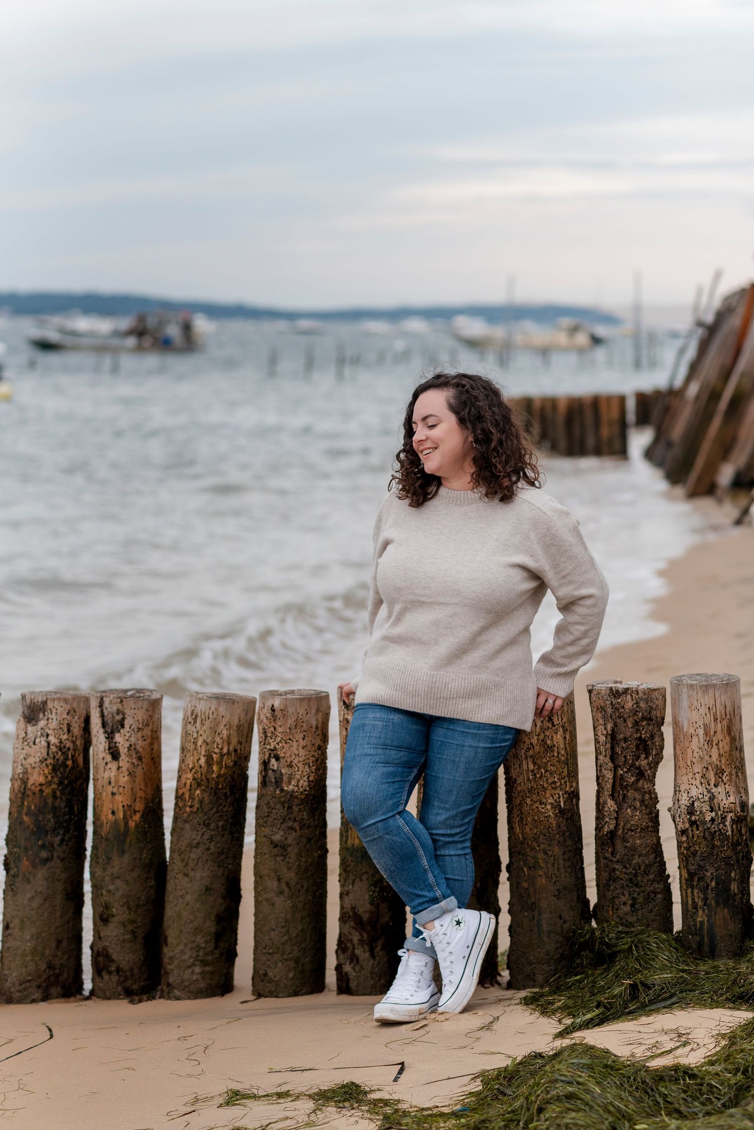 Casual photoshoot at beach with wooden breakwater and ocean waves.