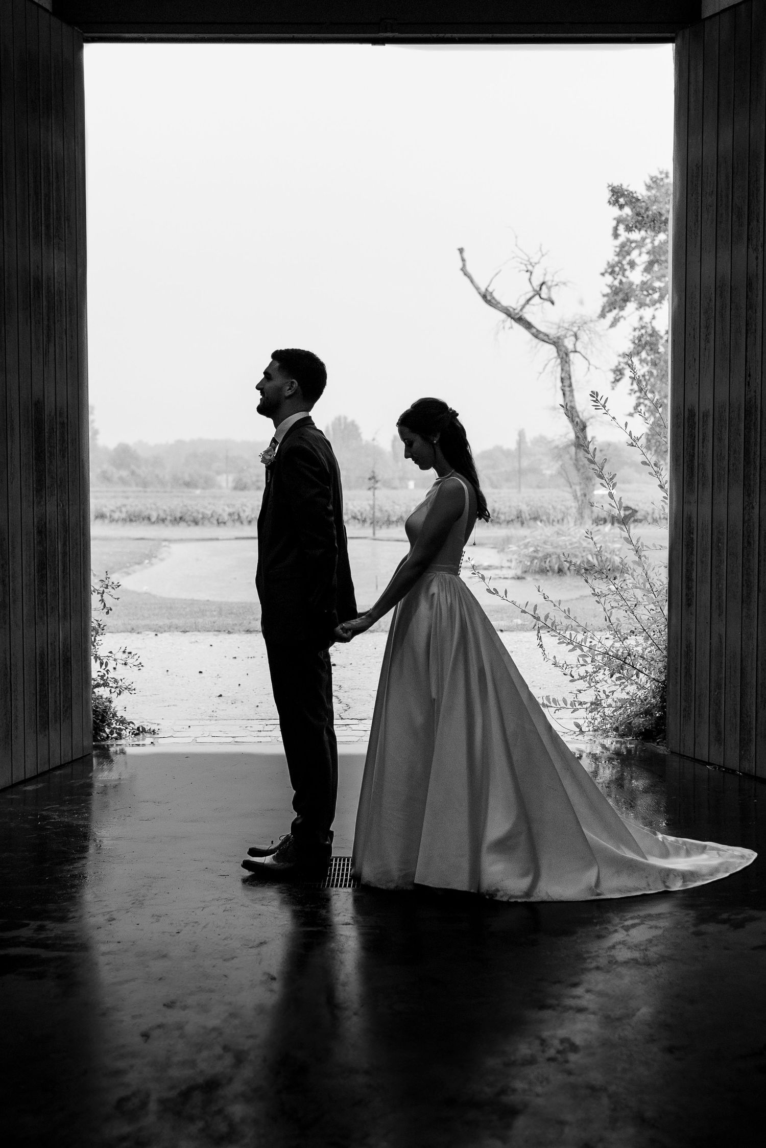 Silhouetted wedding portraits under a covered walkway in dramatic black and white.