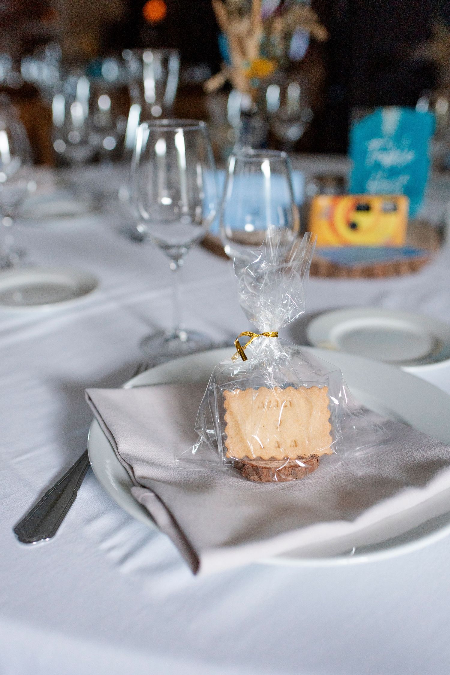 Elegant wedding reception table setting with wrapped favors on white plates.