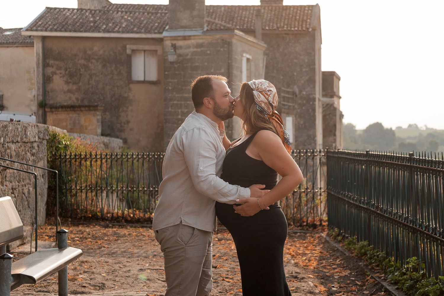 A romantic maternity photo shoot at sunset with a couple embracing on stone steps.