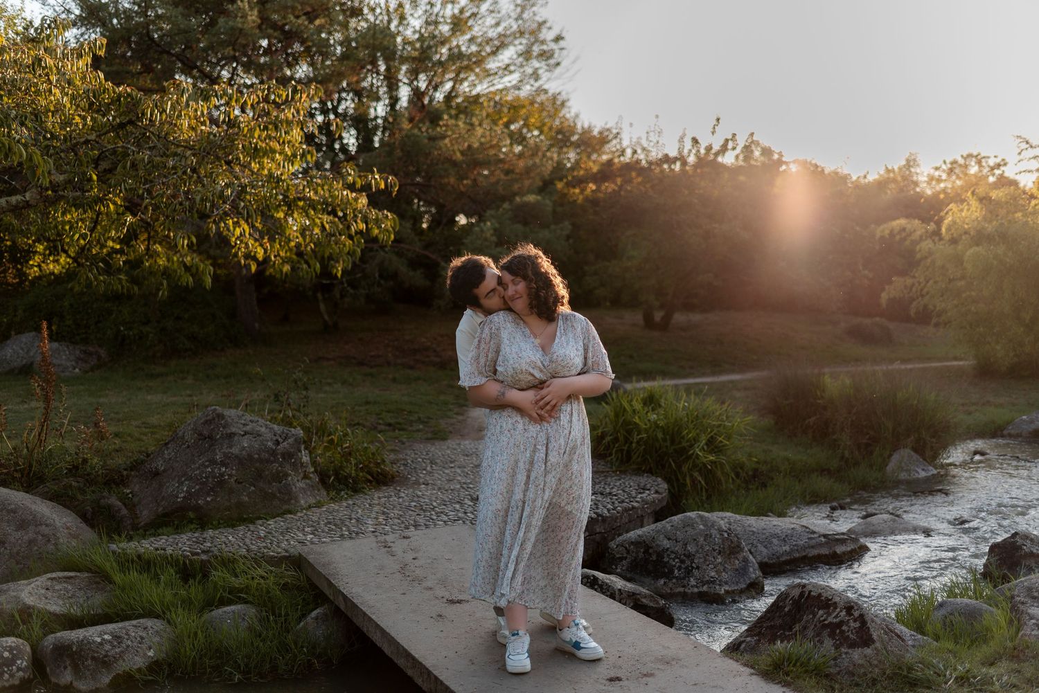 Couple embracing during sunset in a natural outdoor setting with golden light.