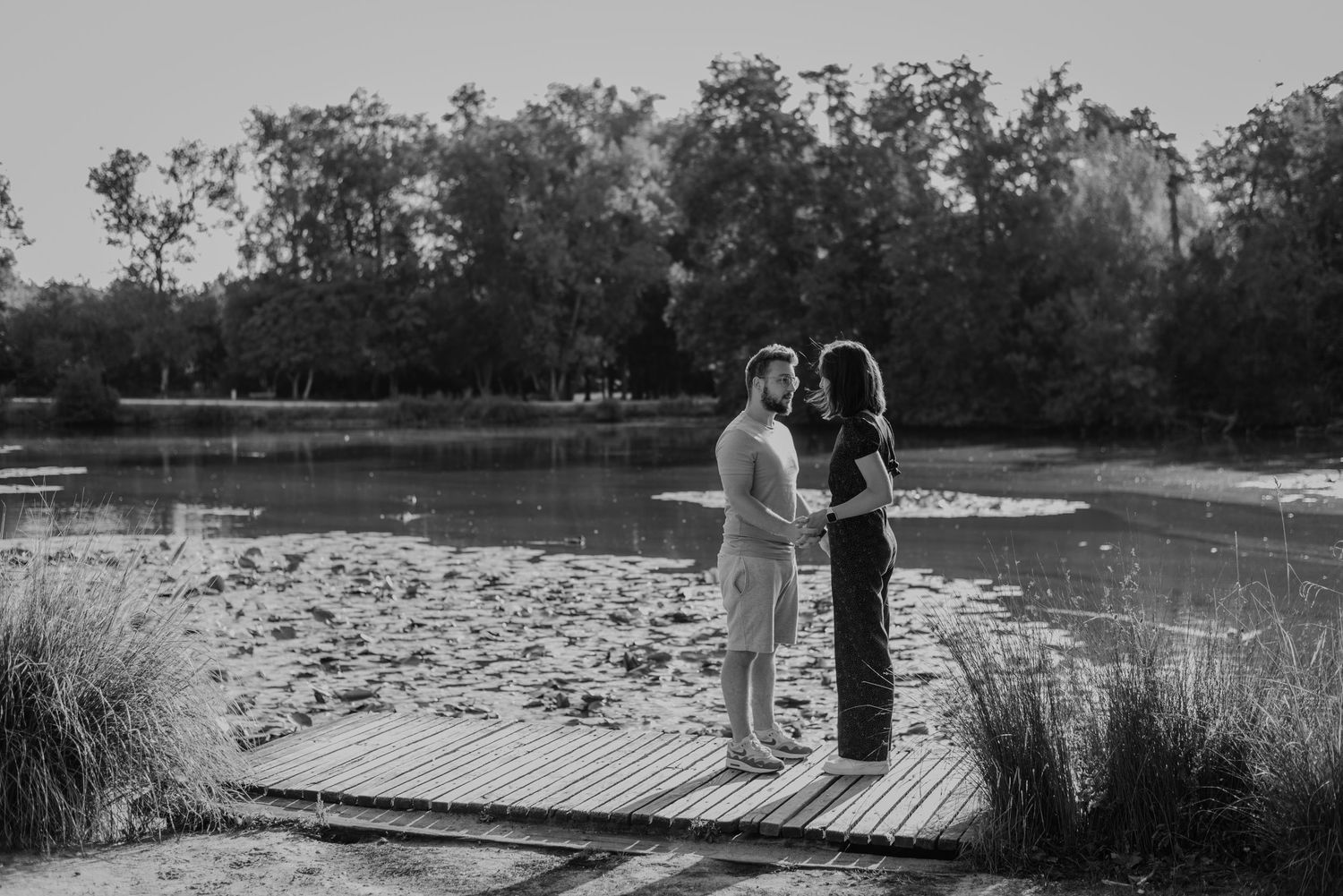 Silhouetted figures walking along wooden boardwalk surrounded by natural landscape.