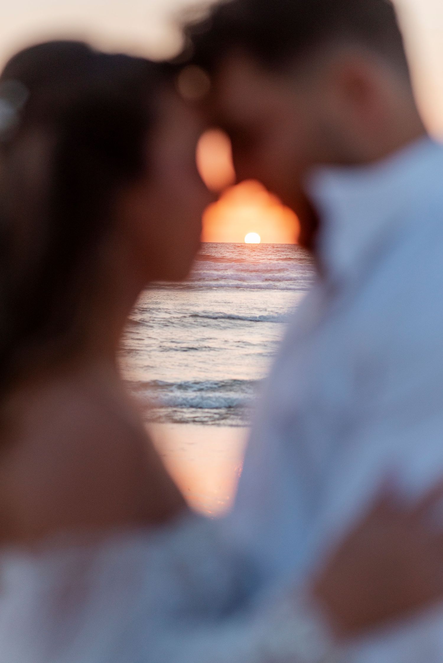 Romantic silhouette of a couple embracing against an ocean sunset background.