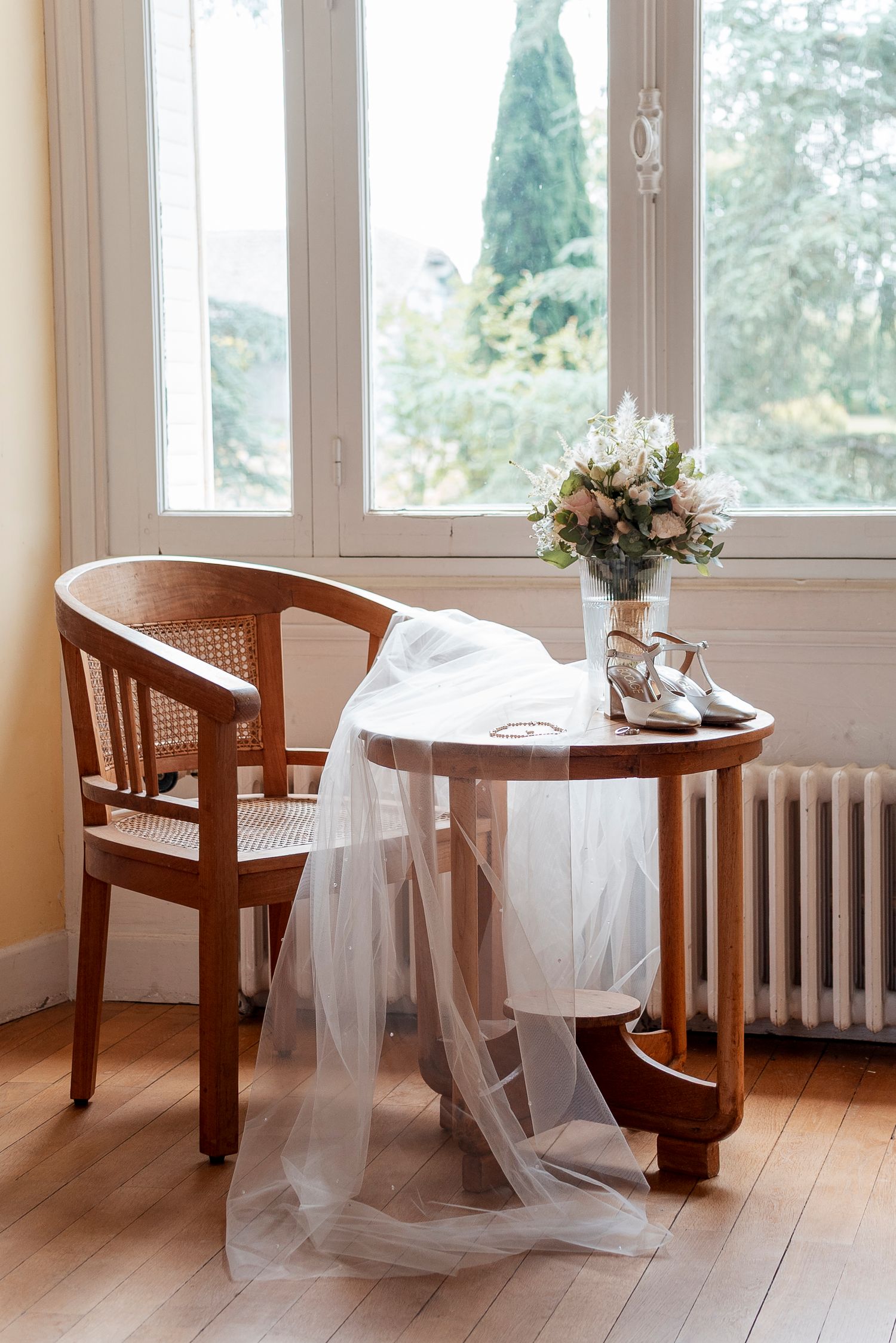 Sunlit room with wooden chairs and delicate white tulle veil draped over furniture.