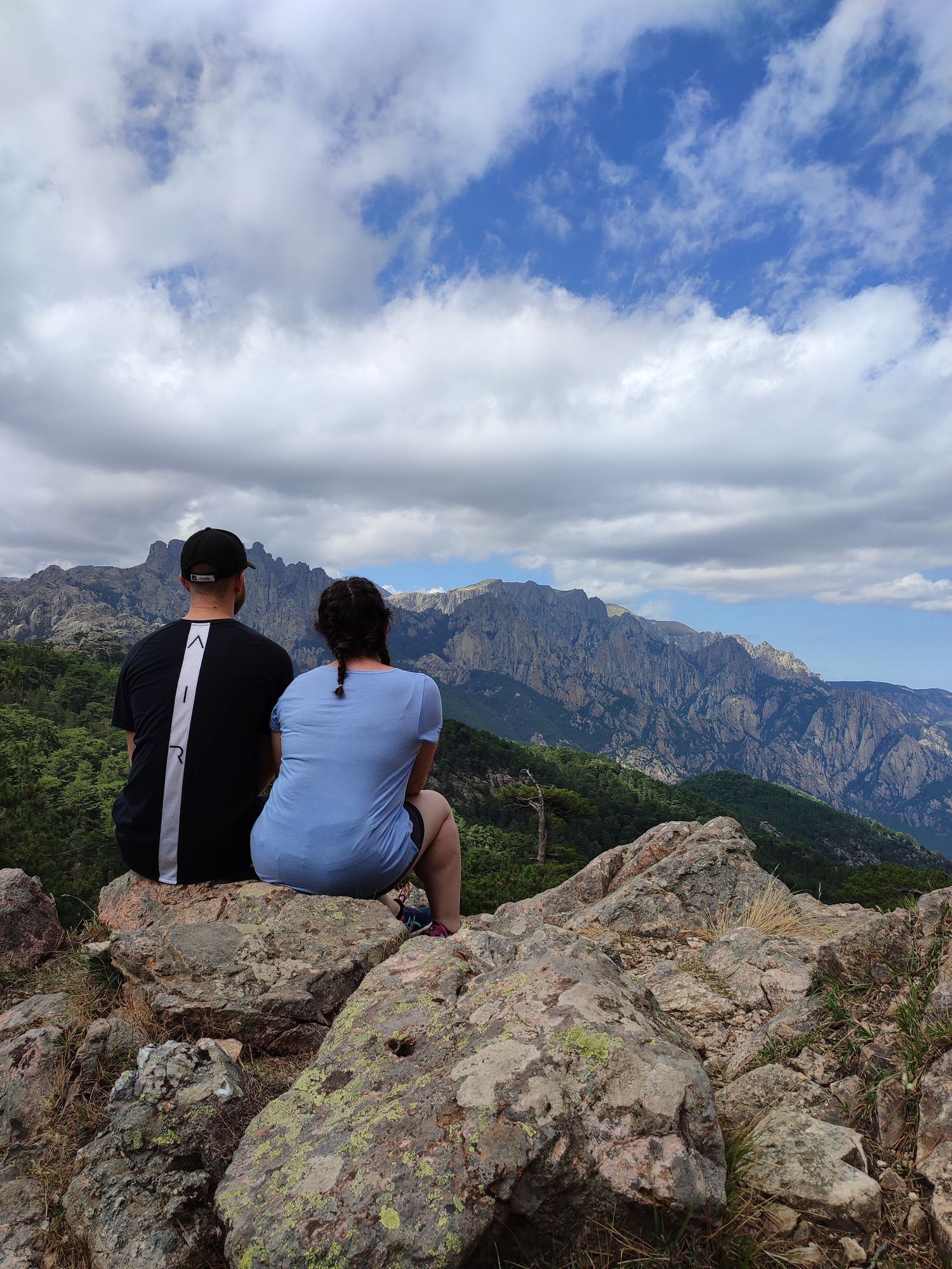 Panoramic mountain vista with rocky outcrop and cloudy blue skies.
