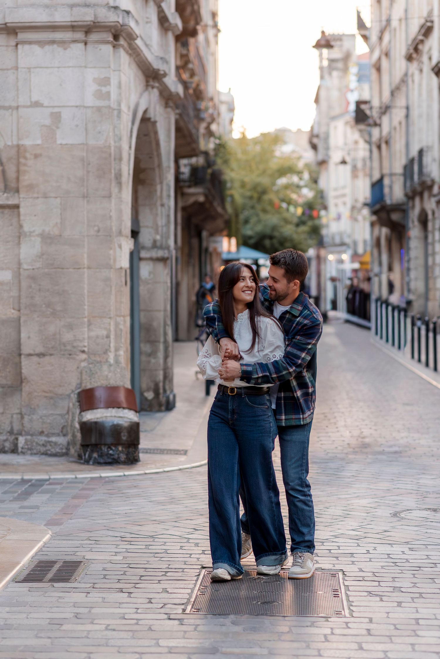 A couple shares a romantic moment on a historic cobblestone street.
