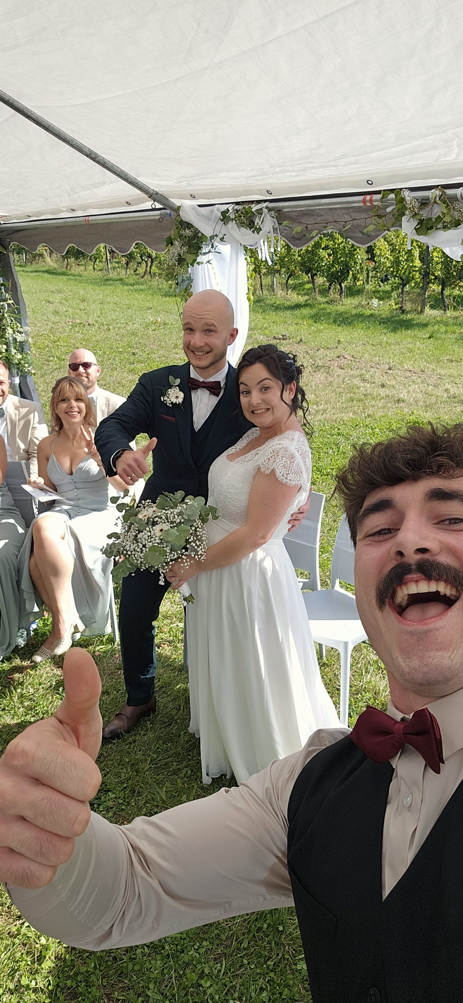 Wedding celebration under white tent with guests in formal attire outdoors.