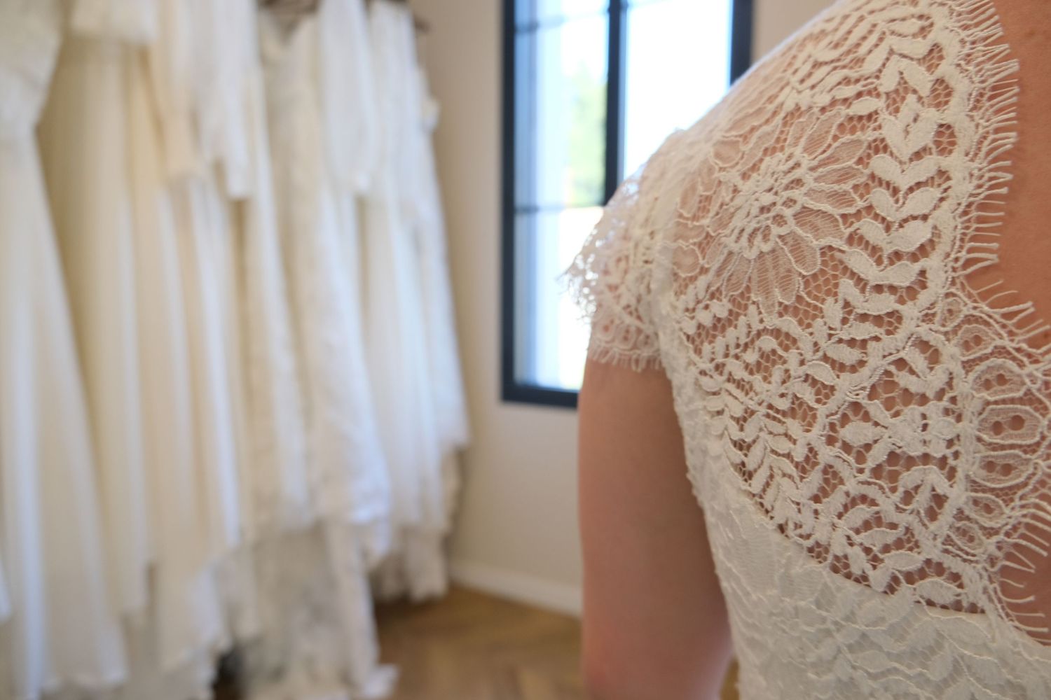 Collection of white lace wedding dresses hanging in bridal boutique.