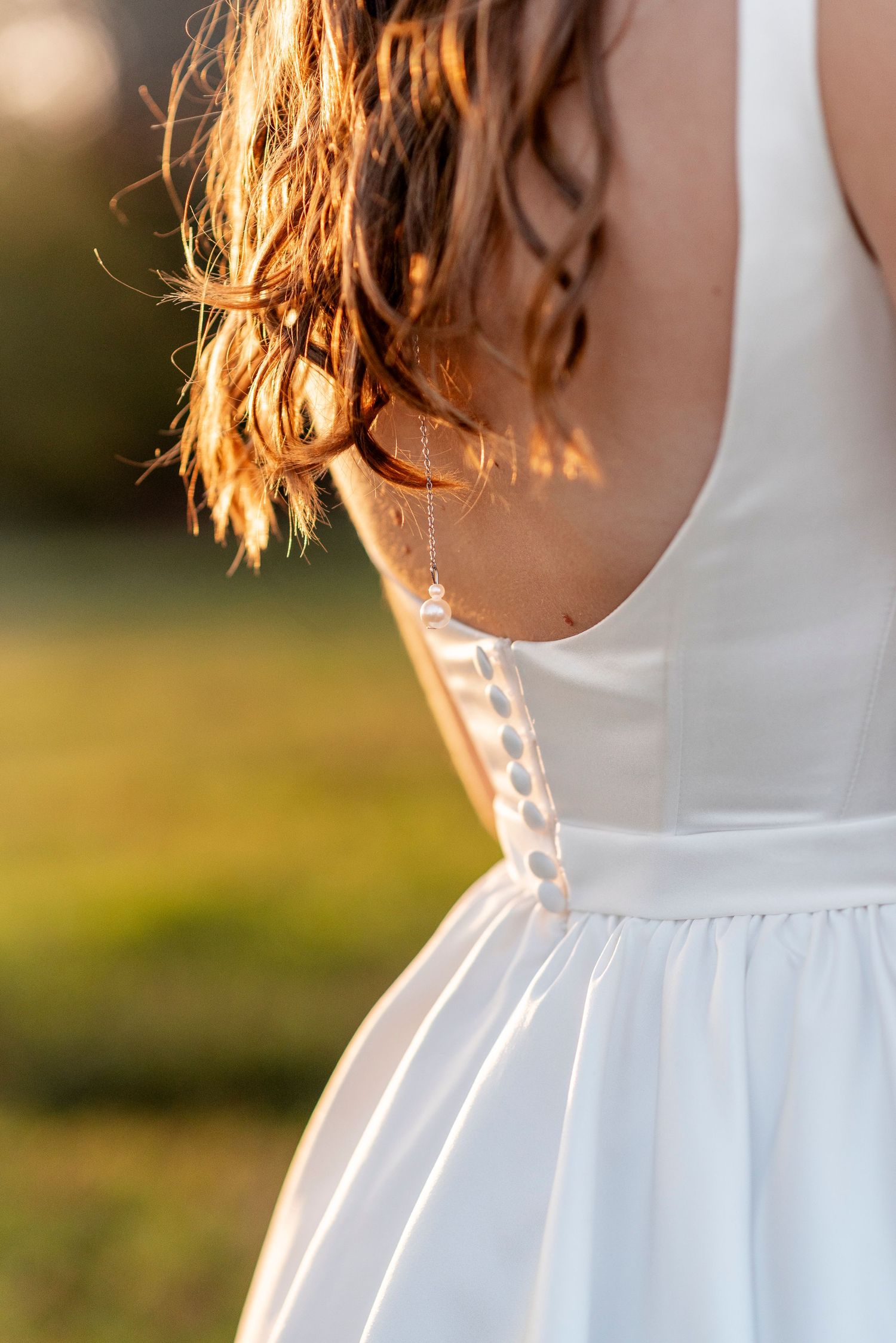 Elegant white wedding dress detail backlit by golden sunset light.