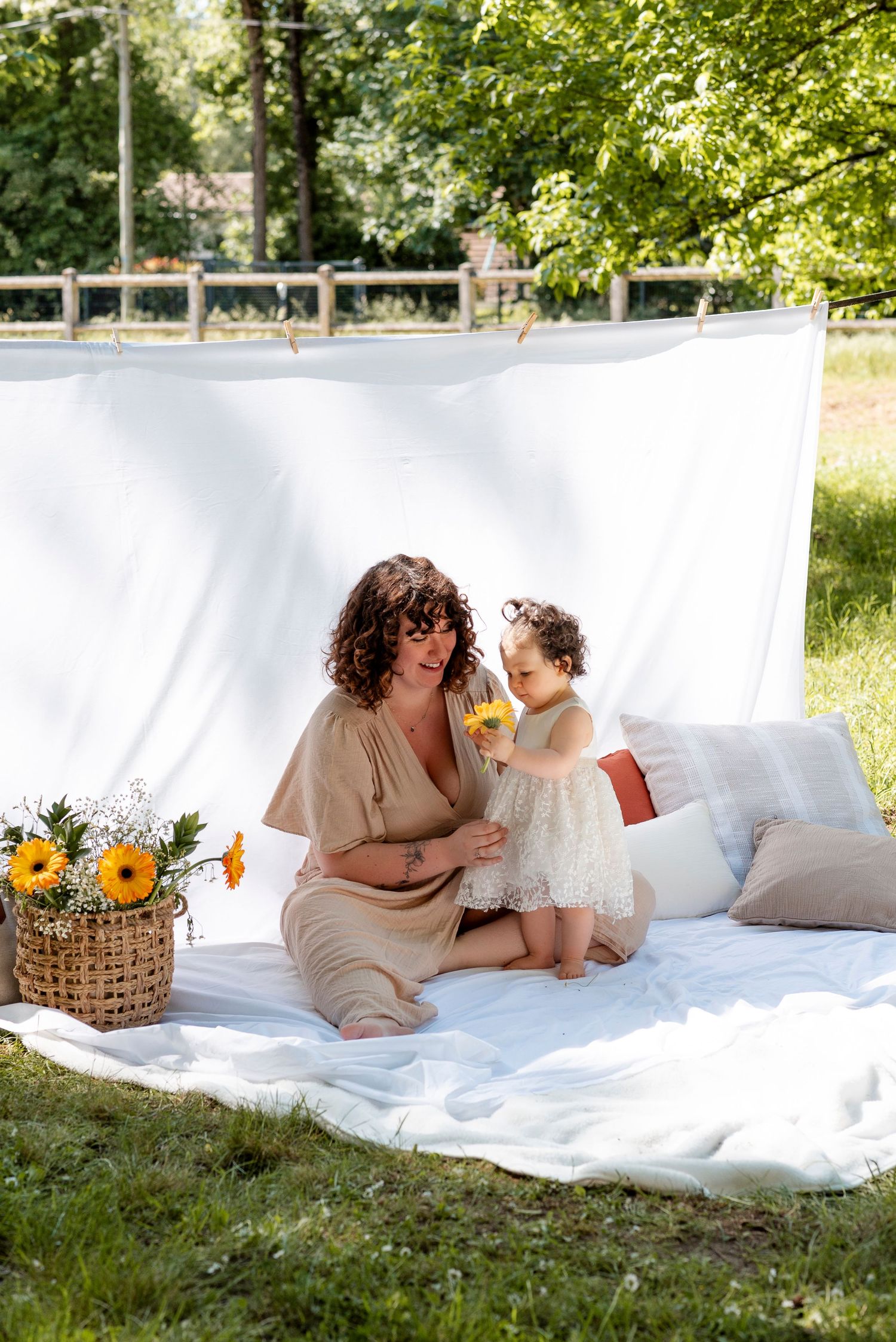 Outdoor picnic scene with sunflowers and white backdrop on sunny summer day.