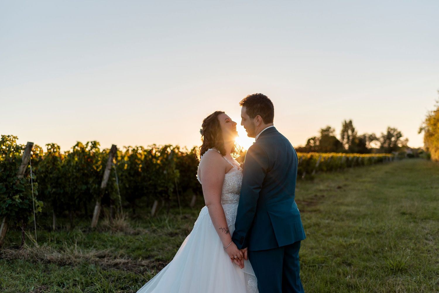Silhouetted wedding couple embracing during golden hour in outdoor field.