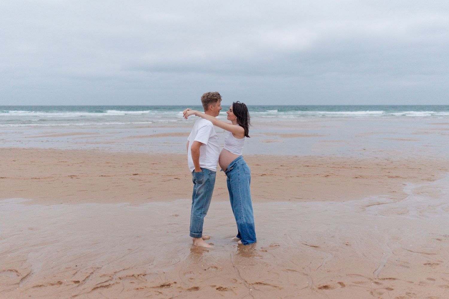 Romantic couple shares intimate moments together on a sandy beach at sunset.