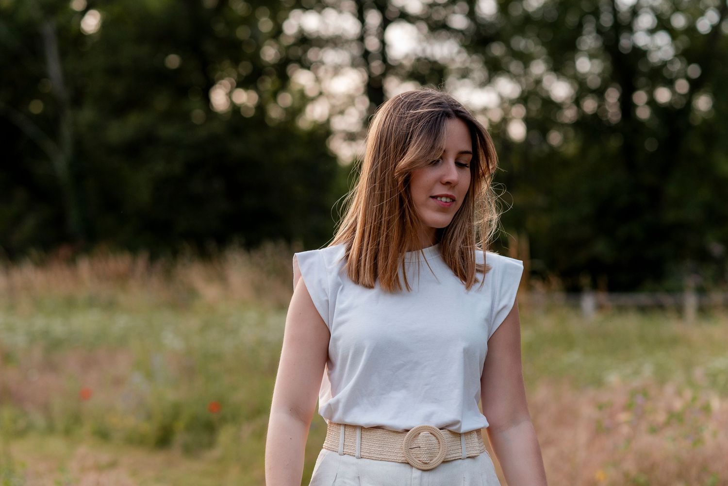 Couple in matching white t-shirts walking through a sunny meadow during a photo session.