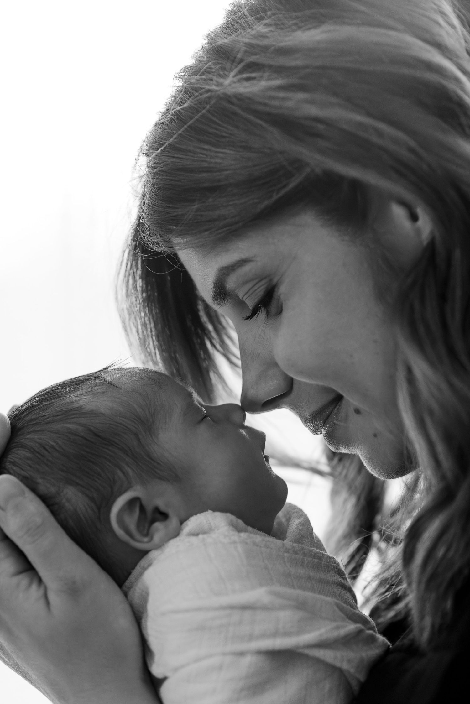 Intimate black and white portrait of tender moment between parent and newborn.