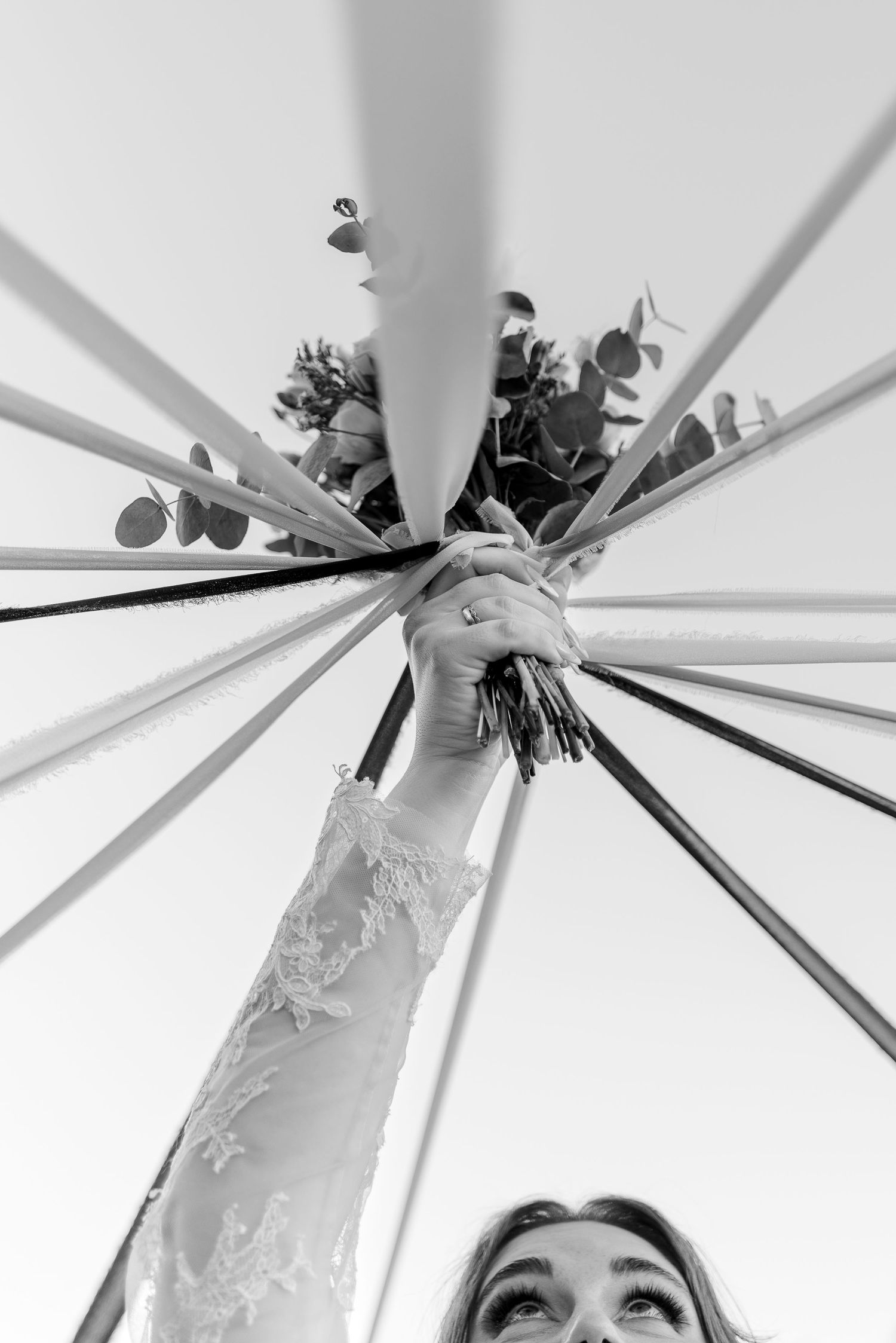 Wedding reception decor with white floral arrangements hanging from a modern geometric structure.