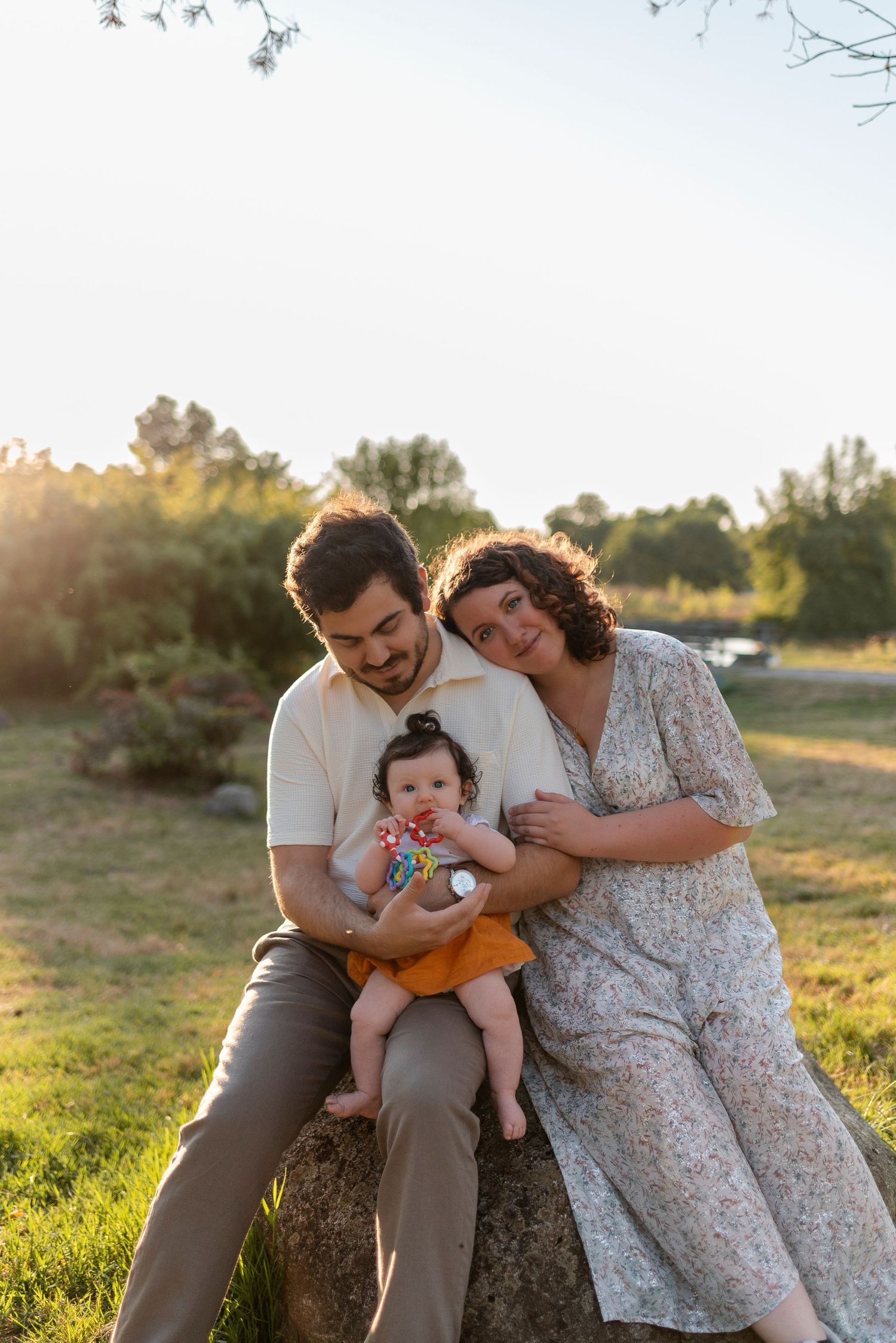 Family sitting together on grass during sunset for an outdoor photo session.