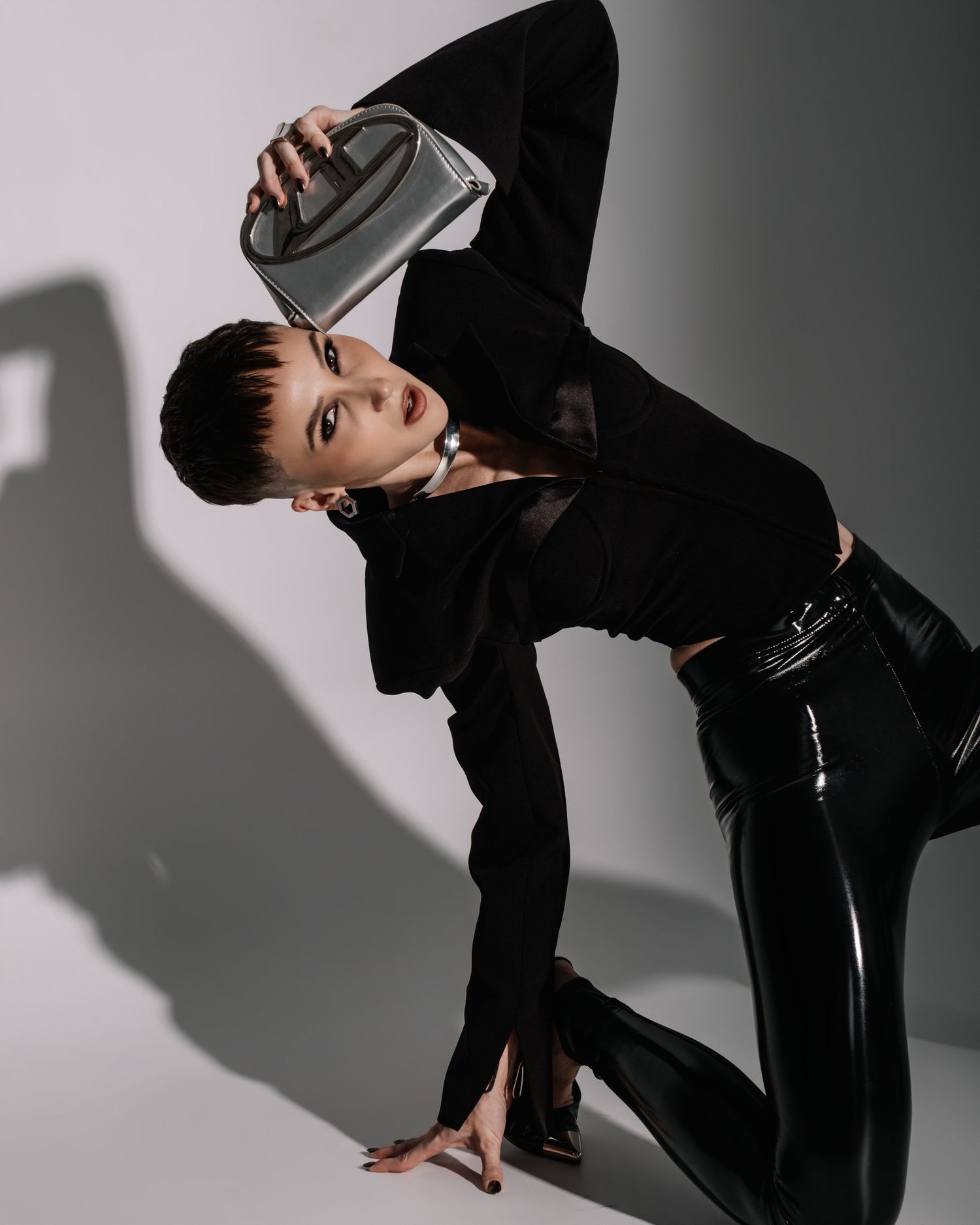 A dancer in black attire performs a dynamic movement sequence against a stark white background with dramatic shadows.