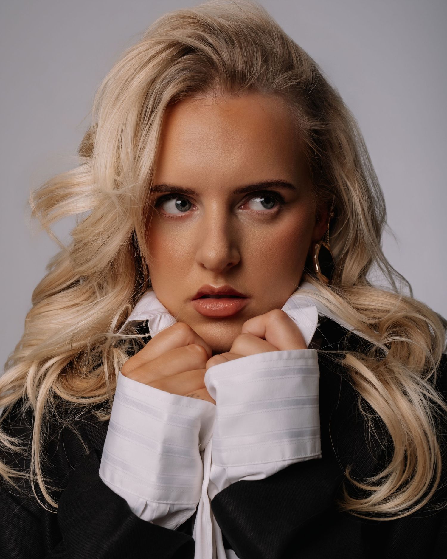 Artistic portrait series showing blonde hair and a white collar against a dark background in dramatic lighting.