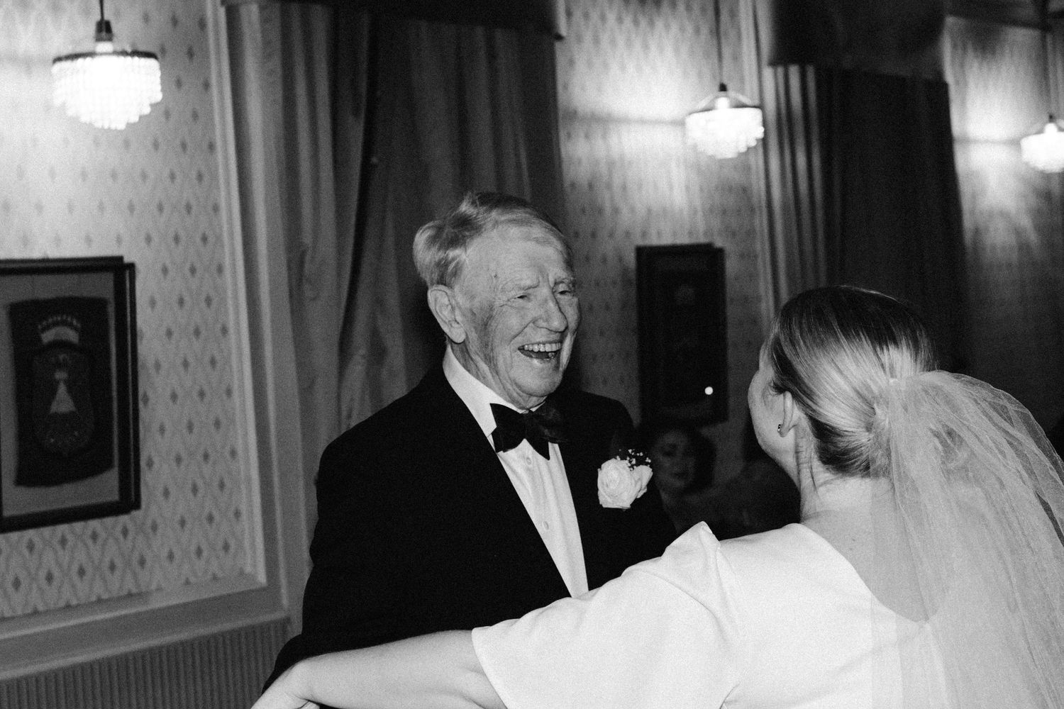 Indoor wedding reception moments captured in black and white with elegant lighting.