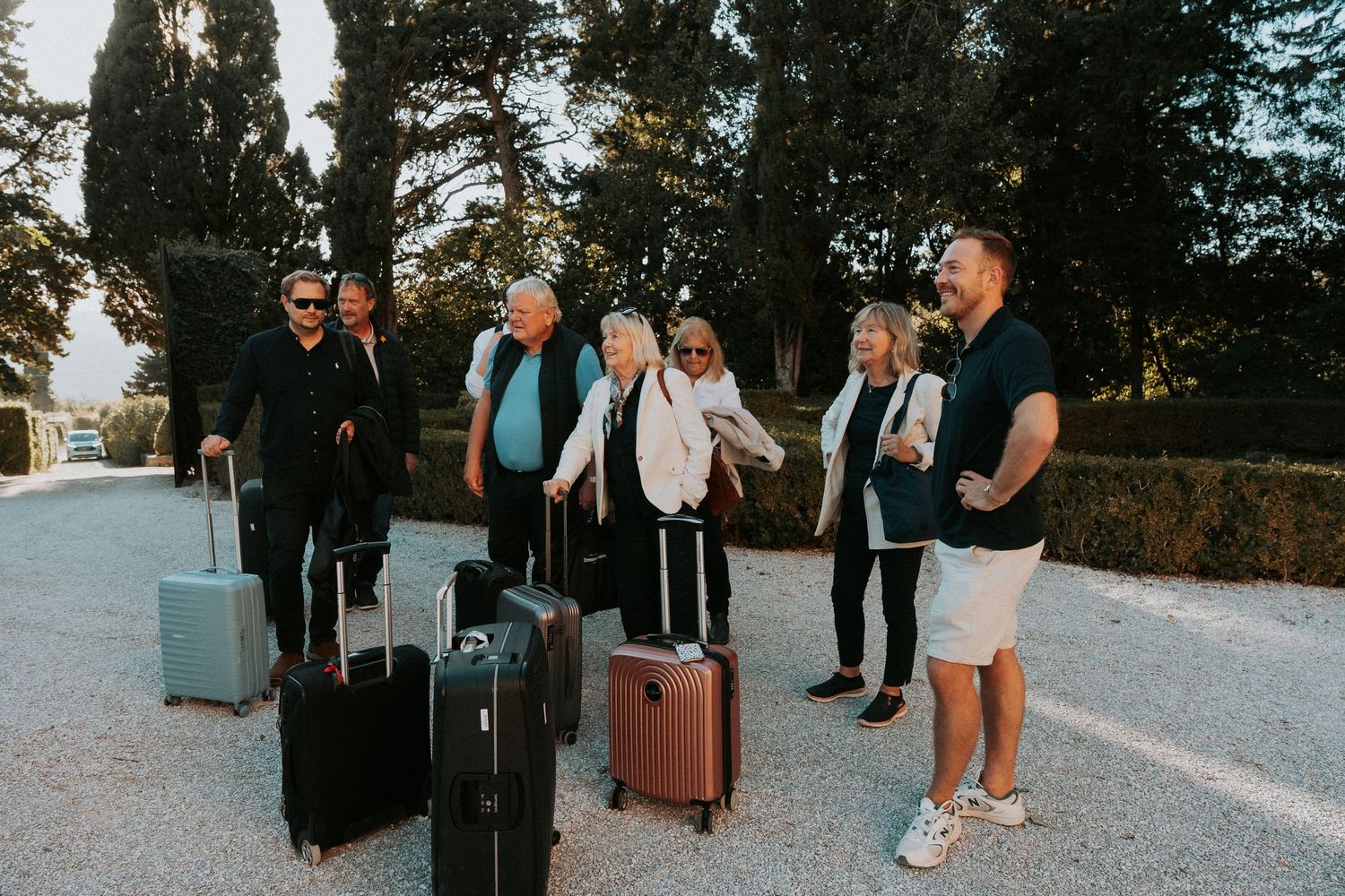 Travelers with luggage gathered outside a Mediterranean villa.