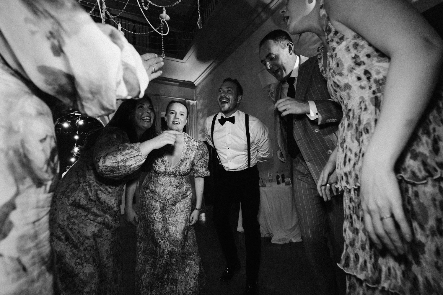 Black and white photo of wedding guests dancing at an evening reception.