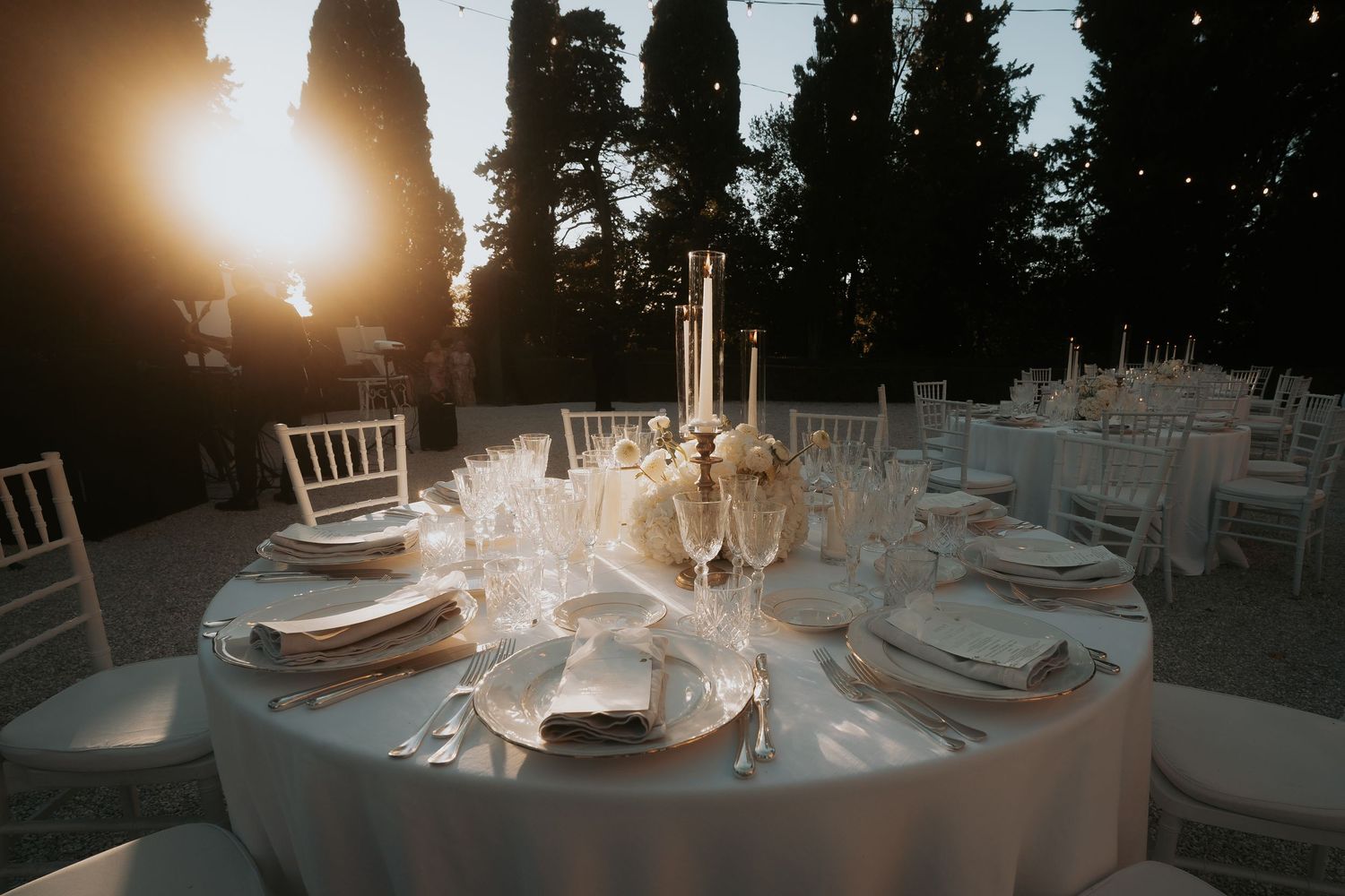 Outdoor wedding reception tables set against a dramatic sunset with mountain views in the background.