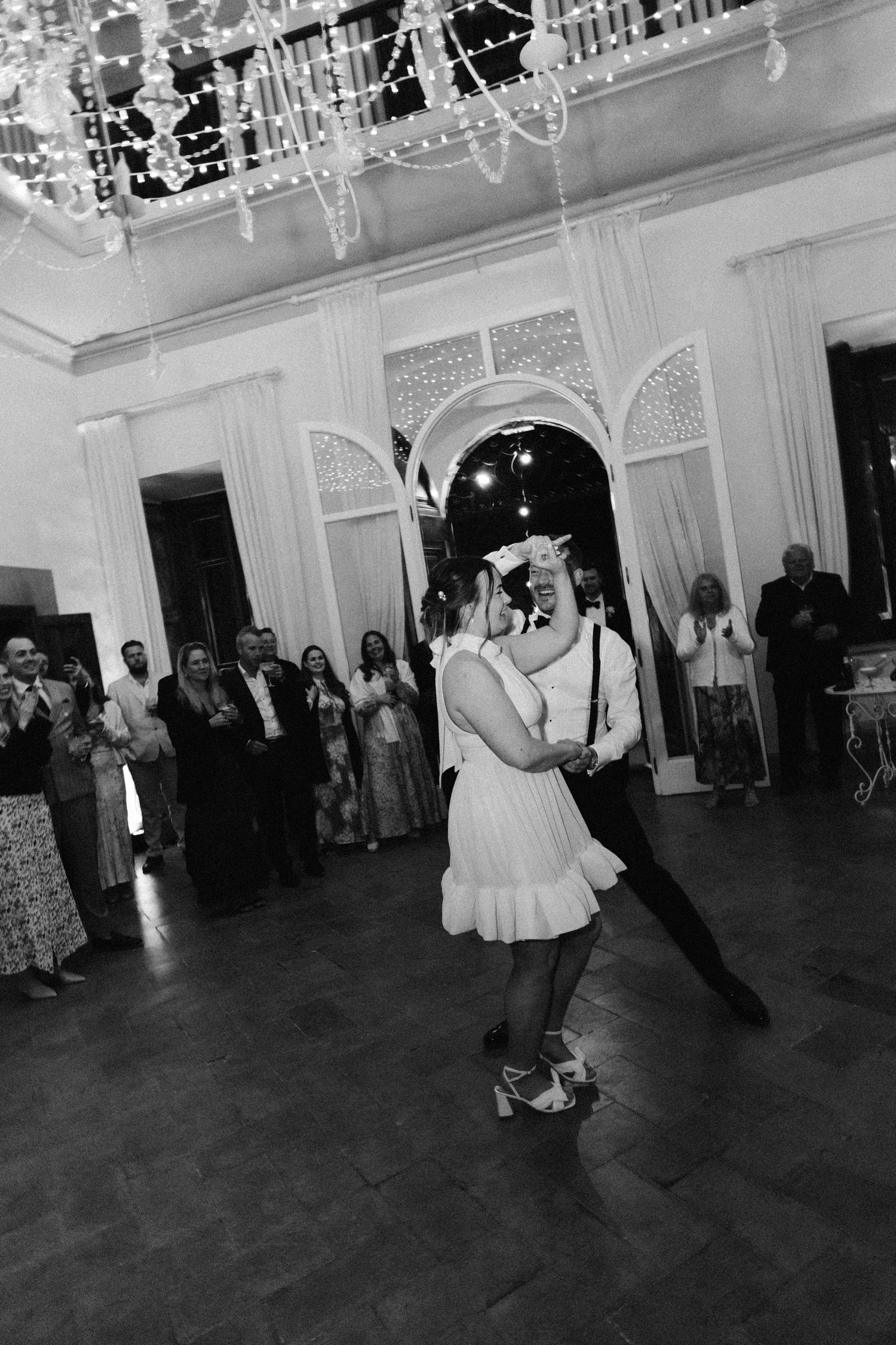 Black and white photo of couples dancing at an elegant indoor wedding reception.
