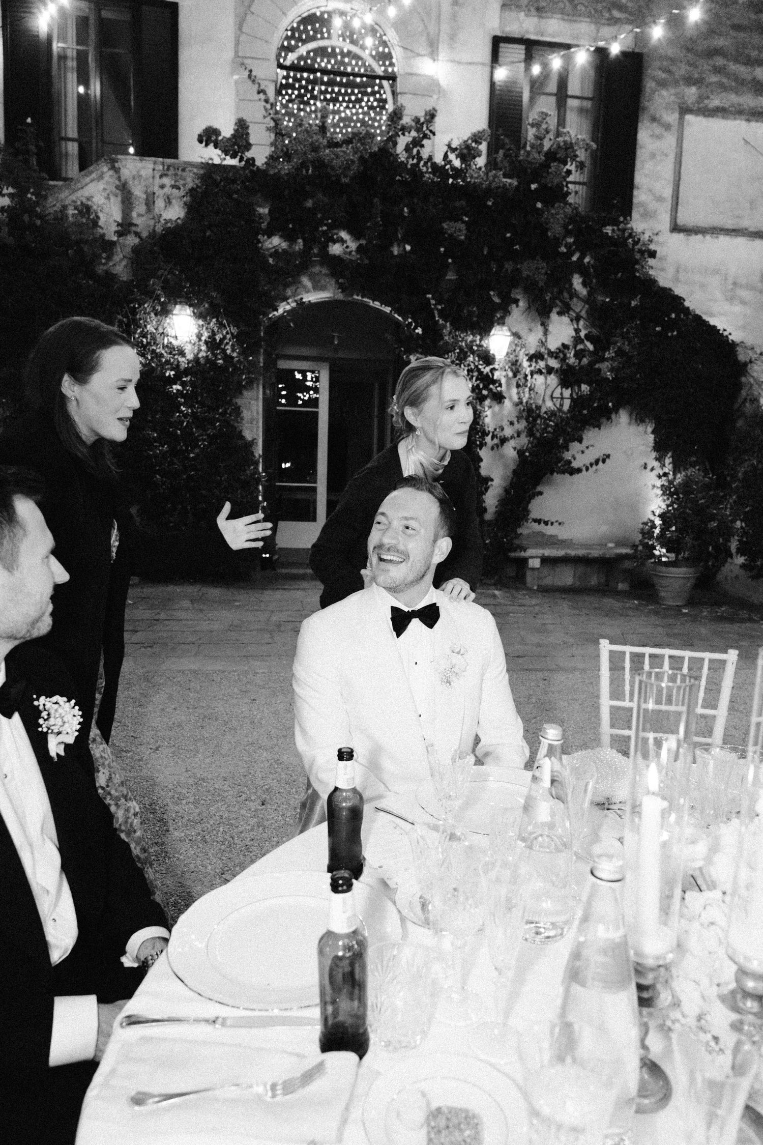 Black and white photo of wedding guests enjoying an elegant dinner reception.
