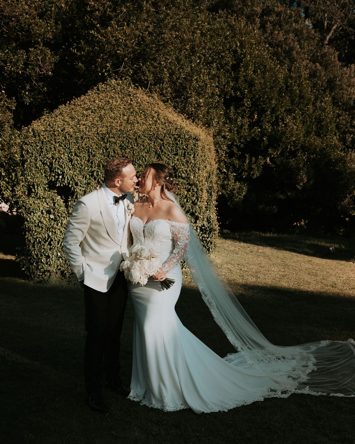 A romantic moment captured in golden light with a flowing white wedding dress and veil.