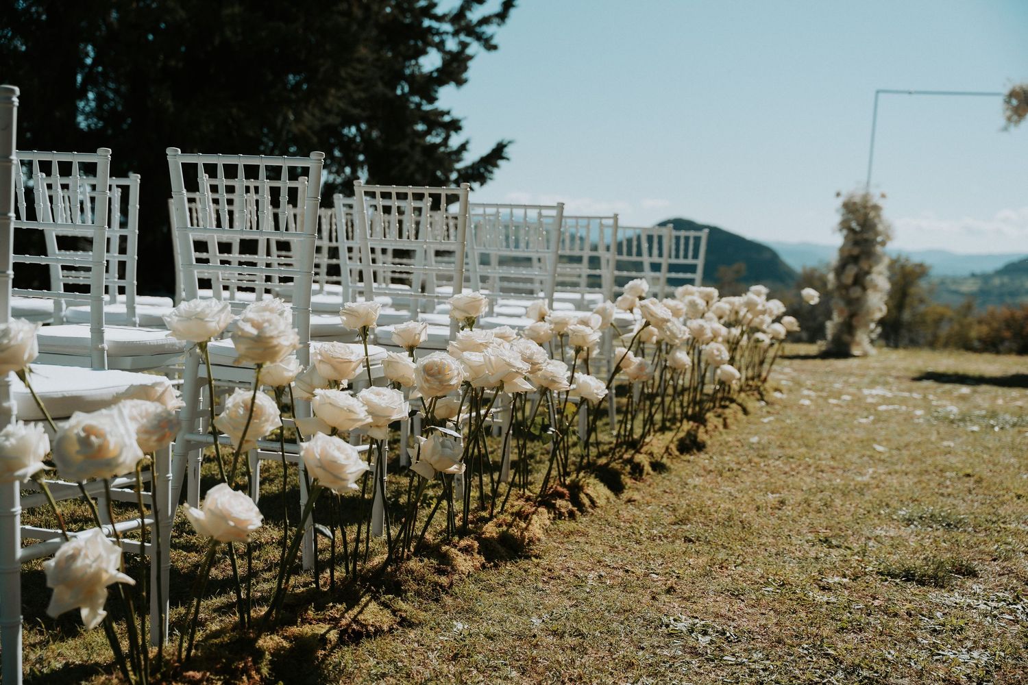 Rows of white chairs set up for outdoor wedding with mountain scenery.