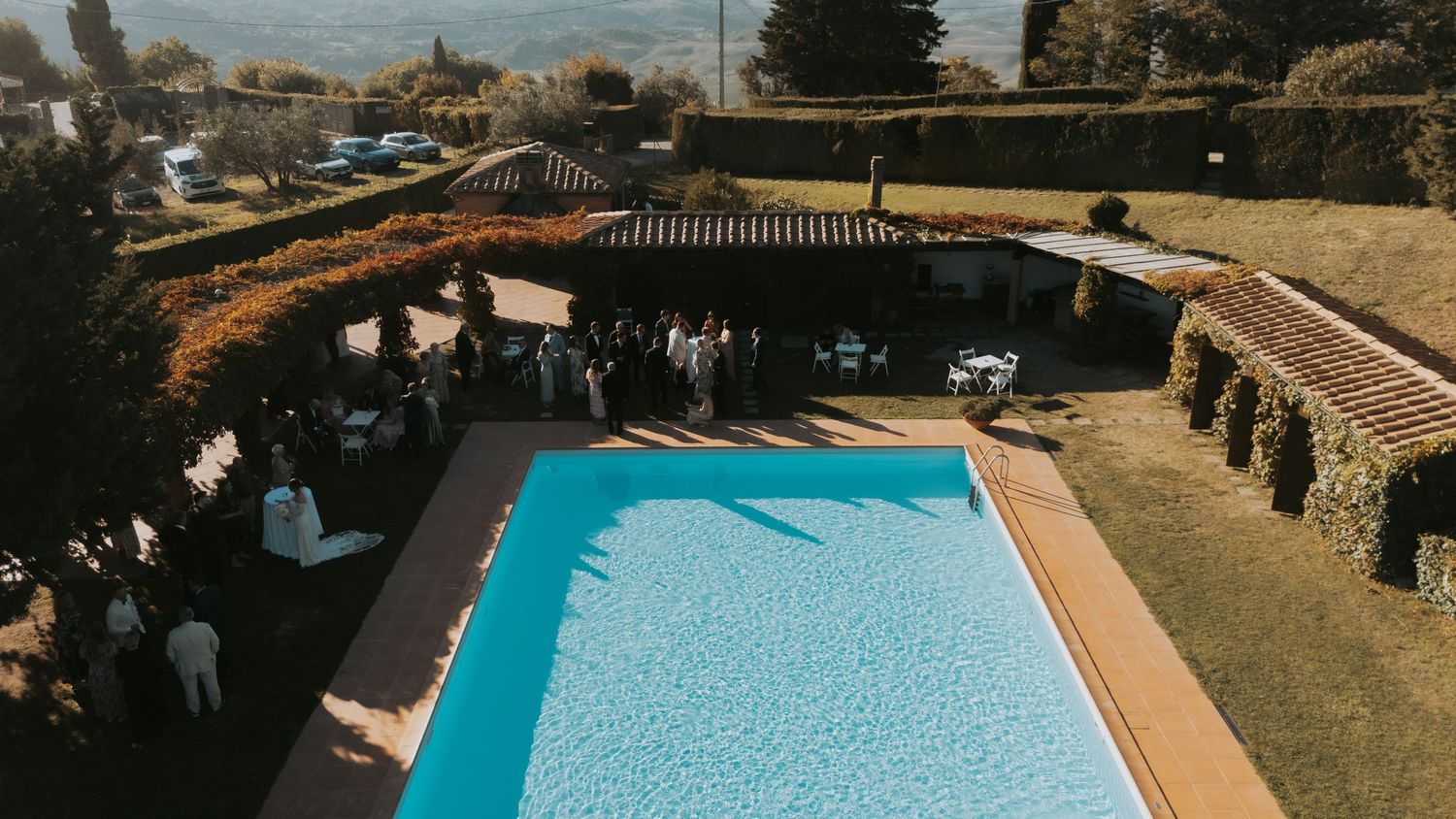 Panoramic view of an elegant outdoor wedding venue with a swimming pool and stone architecture.