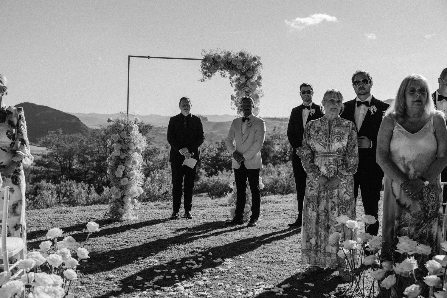 Wedding guests gathered outdoors with mountain scenery in the background.